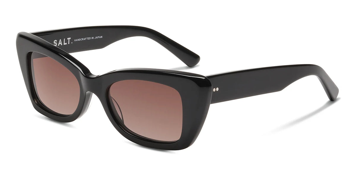 Introducing the SALT. Tory: bold black cat-eye sunglasses featuring thick Japanese acetate frames and brown tinted lenses. The inner temples display crisp white SALT. branding, signifying their exceptional Japanese craftsmanship. For a refined touch, two small silver dots accent the temple near the hinge.