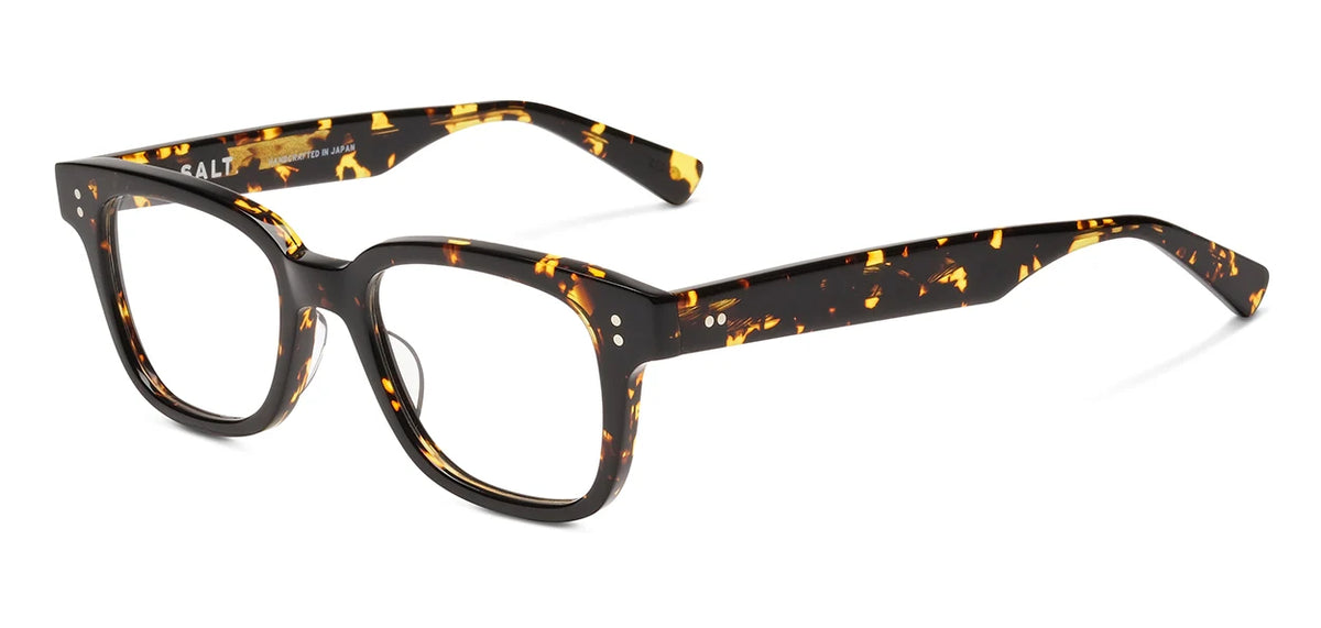 The SALT. Max eyeglasses by SALT. are handcrafted in Japan from premium Japanese acetate, featuring a rectangular shape with thick frames in a dark brown and amber tortoiseshell pattern. Silver dot accents on the front corners of the temples add a touch of vintage Hollywood-inspired charm.