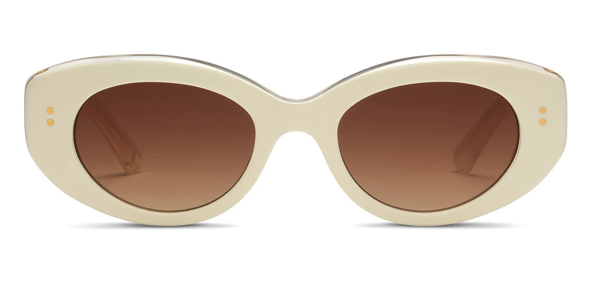 The SALT. Cass sunglasses by SALT. feature cream-colored, oval-shaped frames crafted from premium Japanese acetate, with thick construction and brown-tinted lenses. Viewed from the front, each side of the frame near the hinges is accented by two small gold dots.