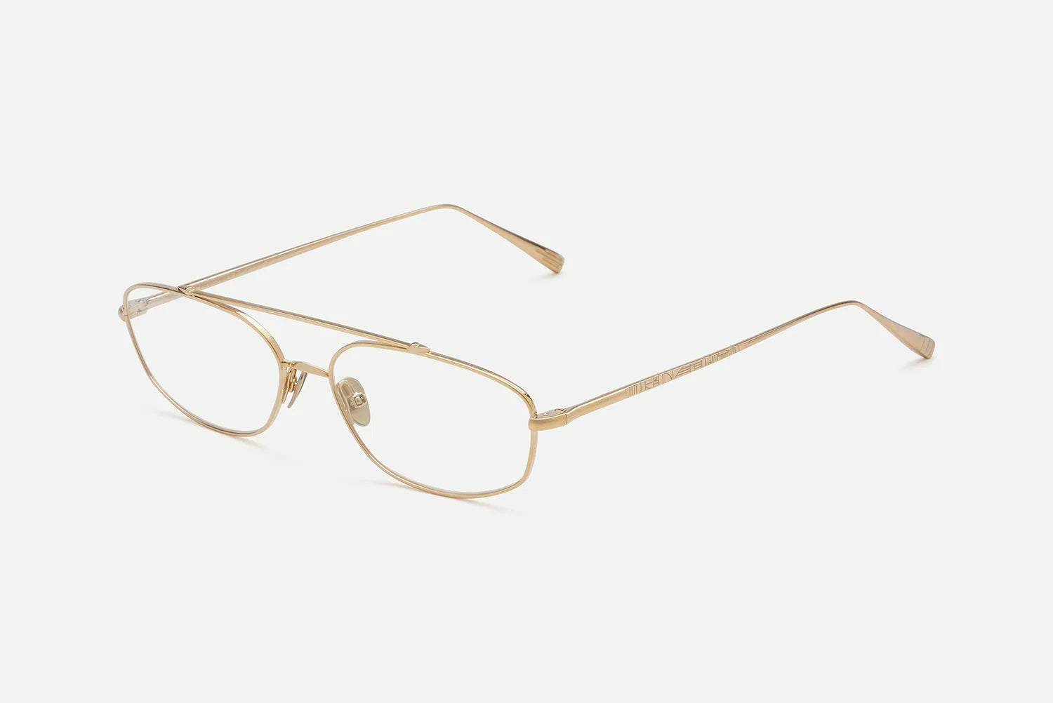 A pair of slim metal eyeglasses with a thin gold-tone frame and clear lenses, shown at an angle on a light gray background.
