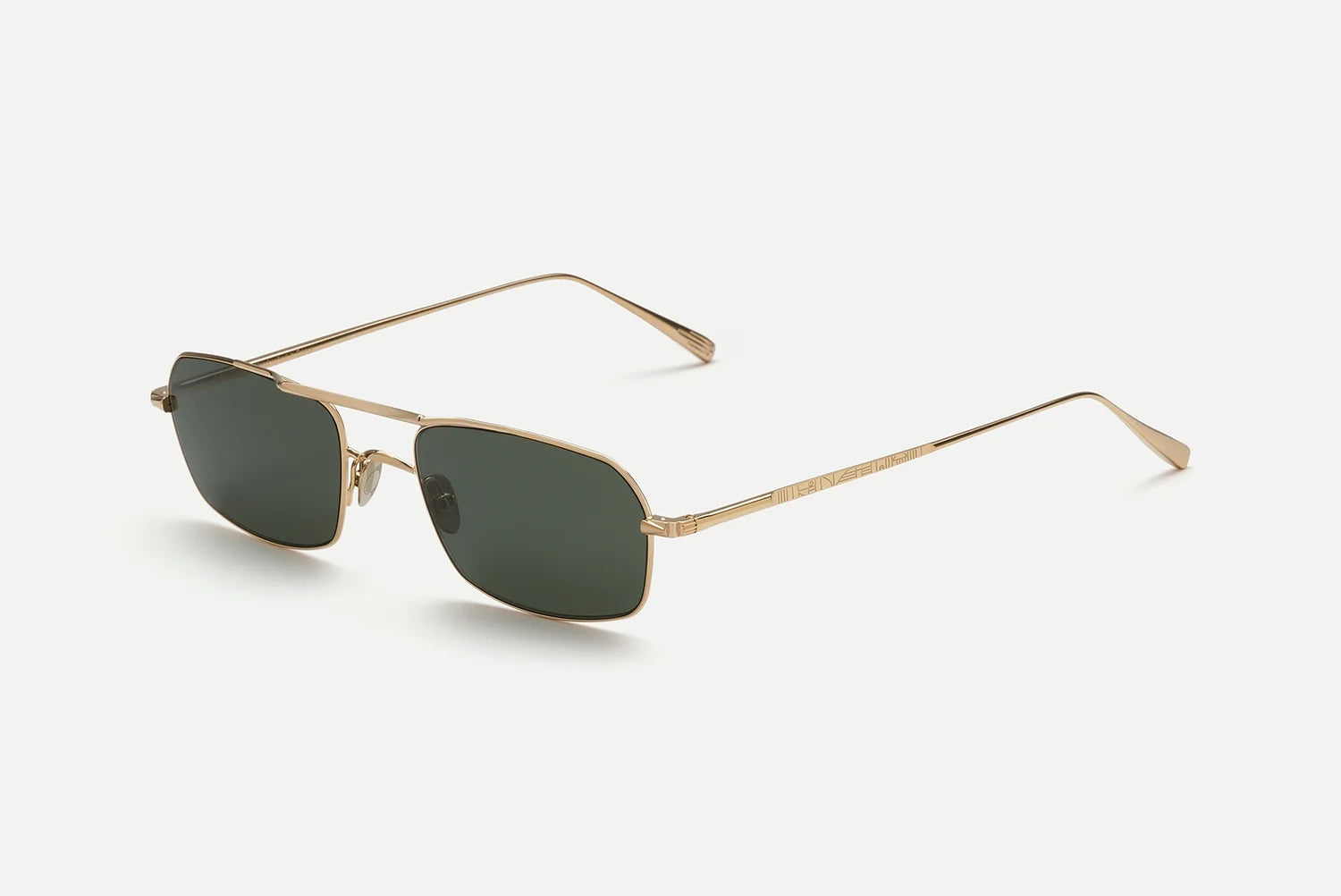 The AHLEM Trevise sunglasses by AHLEM are handcrafted in France from gold metal, featuring dark rectangular lenses, slim frames, and thin temples. Displayed on a white background at an angle that reveals both the front and side, these rectangular aviator sunglasses embody sophistication and timeless style.