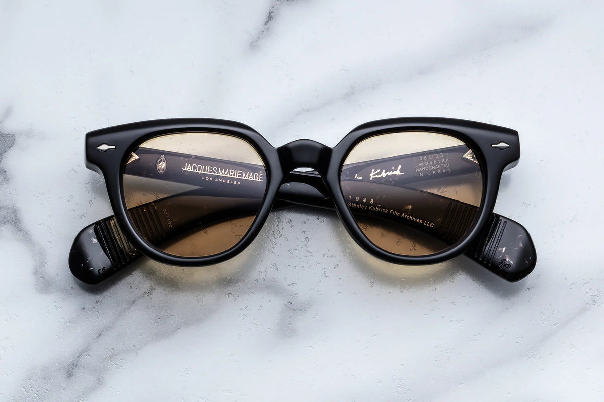 Black-framed Stanley Kubrick by JMM: 1948 glasses with light brown tinted lenses and gold interior temple inscriptions.
