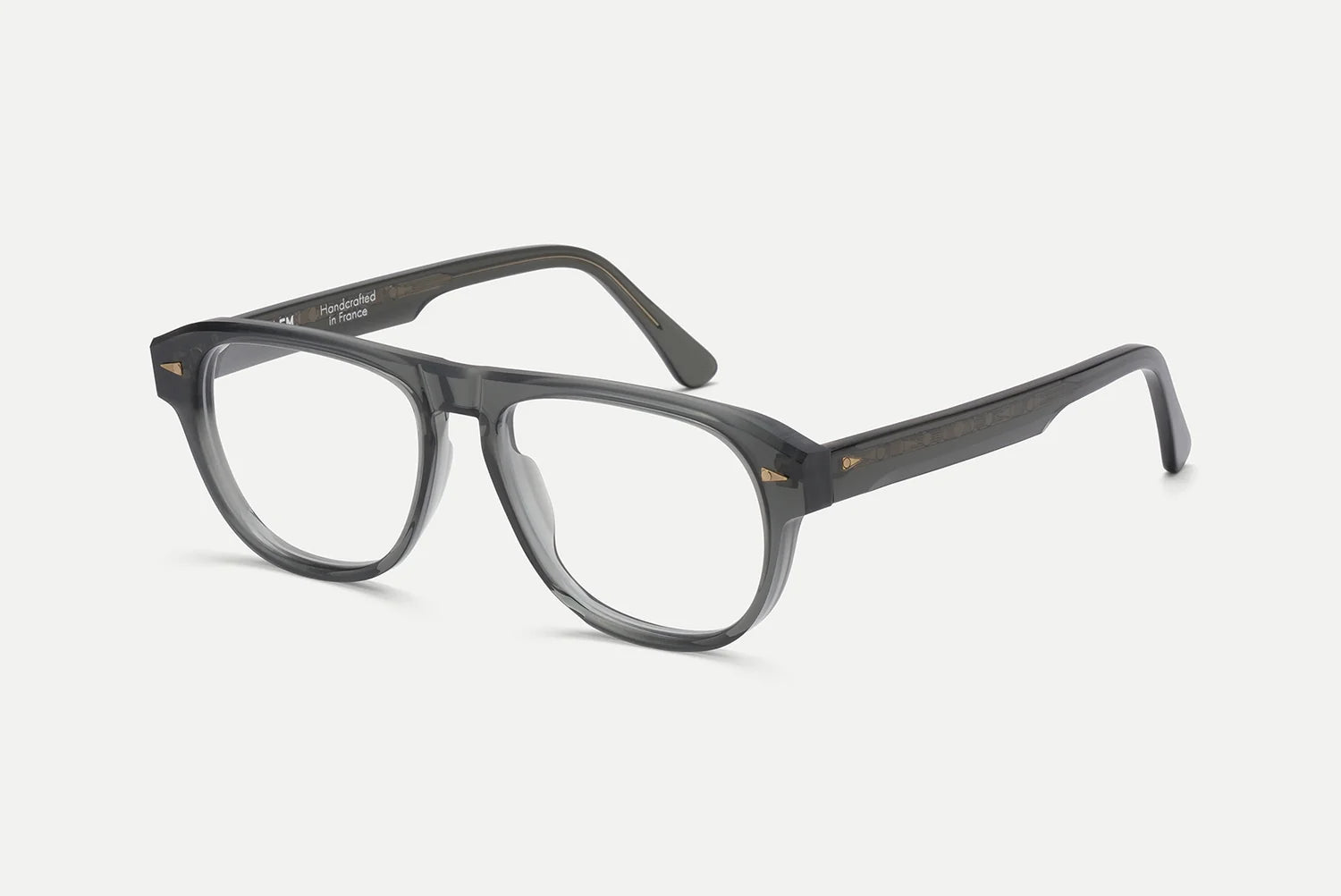 A pair of semi-transparent dark gray acetate eyeglasses with clear lenses, shown at a three-quarter angle on a light gray background.
