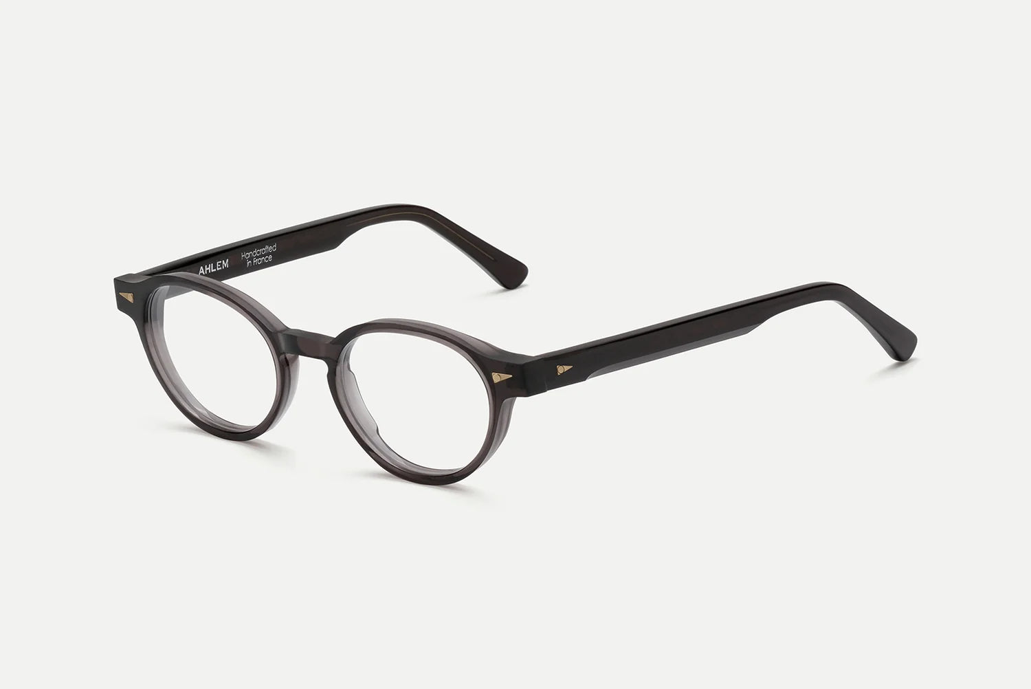 AHLEM St Marcel round black eyeglasses by AHLEM, handcrafted in France from premium Italian acetate with thick frames, feature subtle 22k gold hardware accents on the temples and clear lenses. The glasses are displayed against a plain white background.