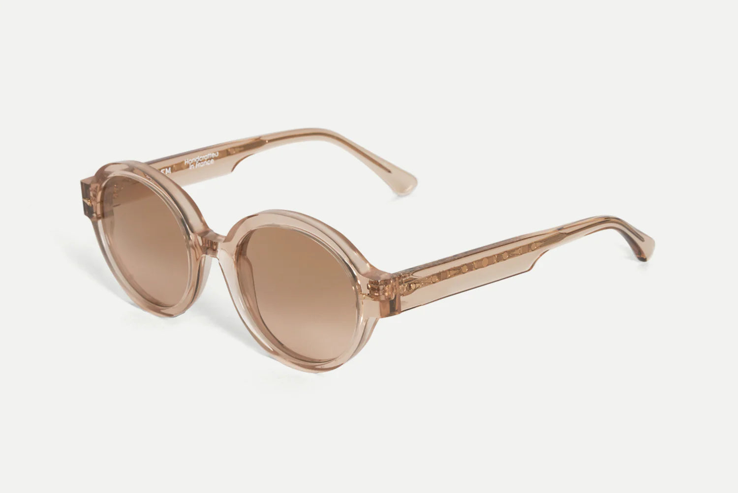 Oval sunglasses with translucent blush pink frames and matching tinted lenses, shown on a light gray background.