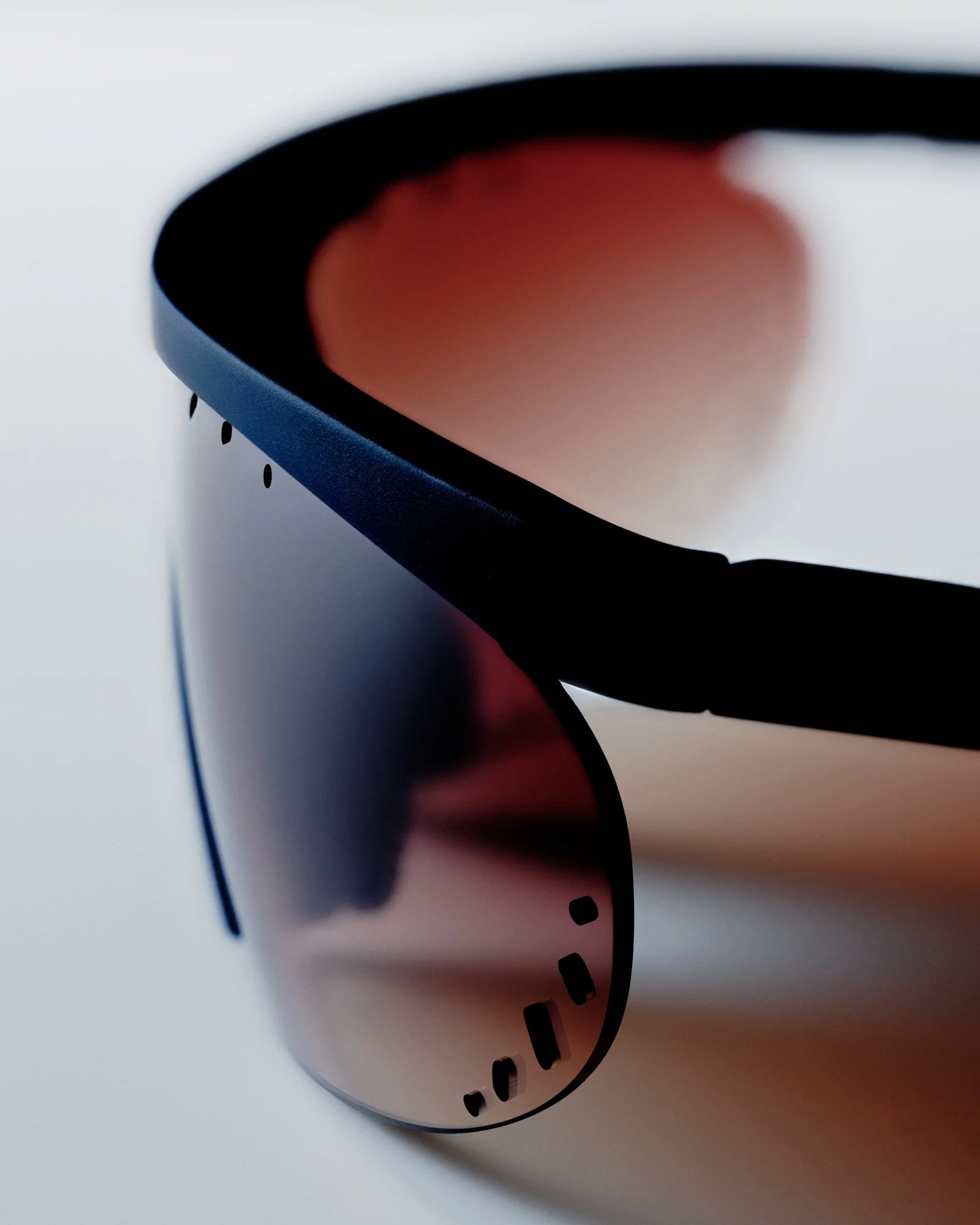 Close-up of a black-framed sunglasses with reflective lenses on a white background