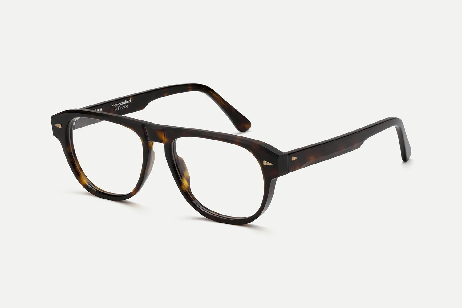 A pair of classic square-frame eyeglasses with a dark brown and amber tortoiseshell acetate frame and clear lenses, photographed on a clean, light gray background.