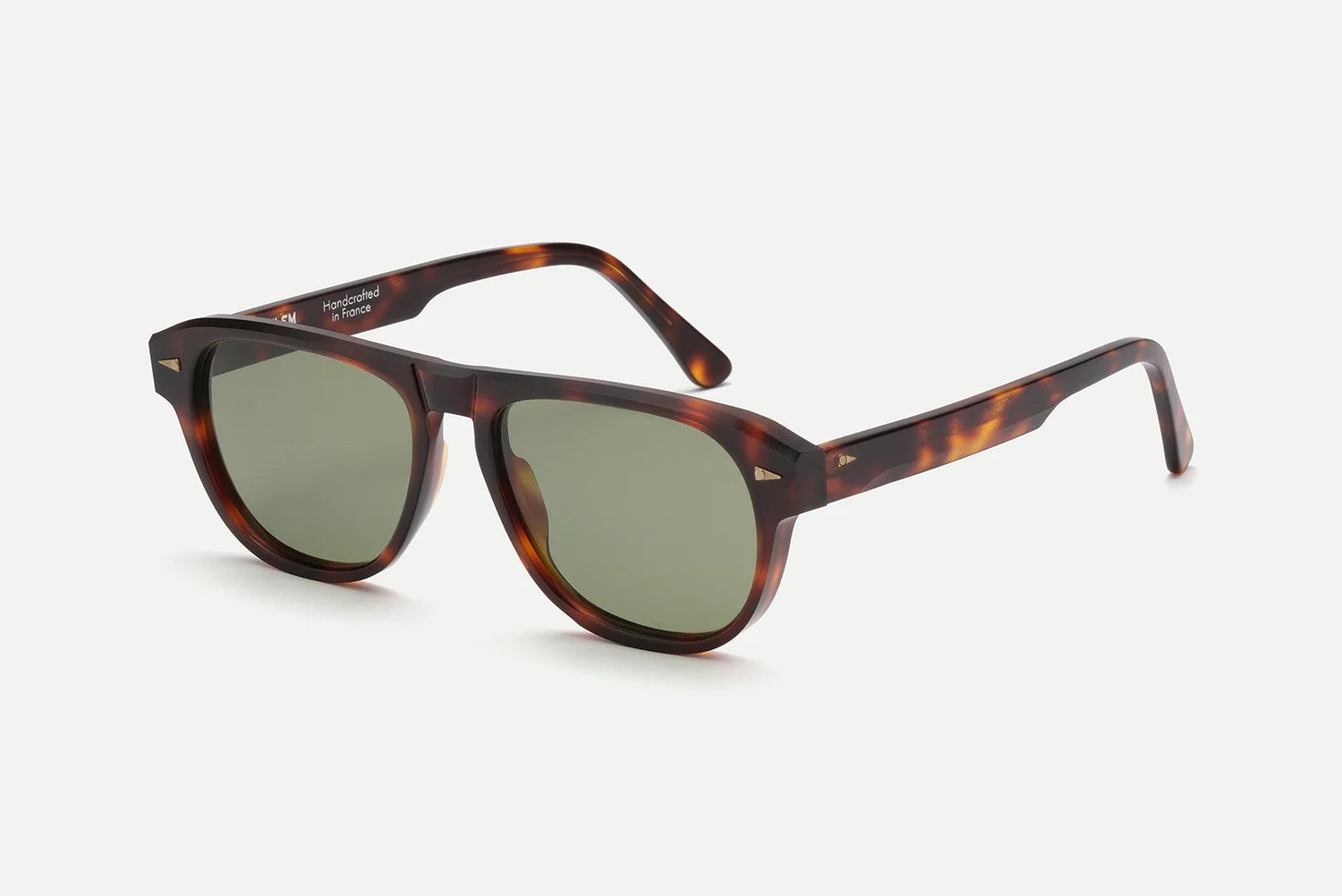 AHLEM Carpentier sunglasses by AHLEM, handcrafted in France from premium Italian acetate, feature a classic round frame in brown tortoiseshell with green lenses and a subtle keyhole bridge, shown on a white background.