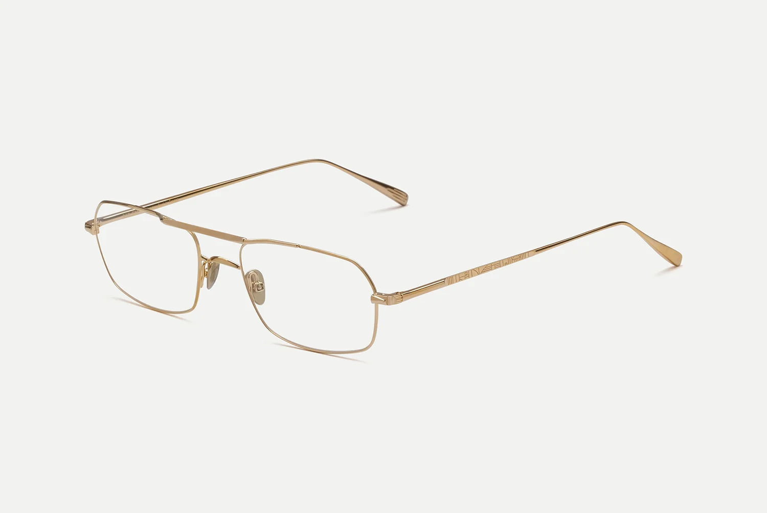 A pair of slim, rectangular metal eyeglasses in a gold finish, displayed on a clean, light off-white background.