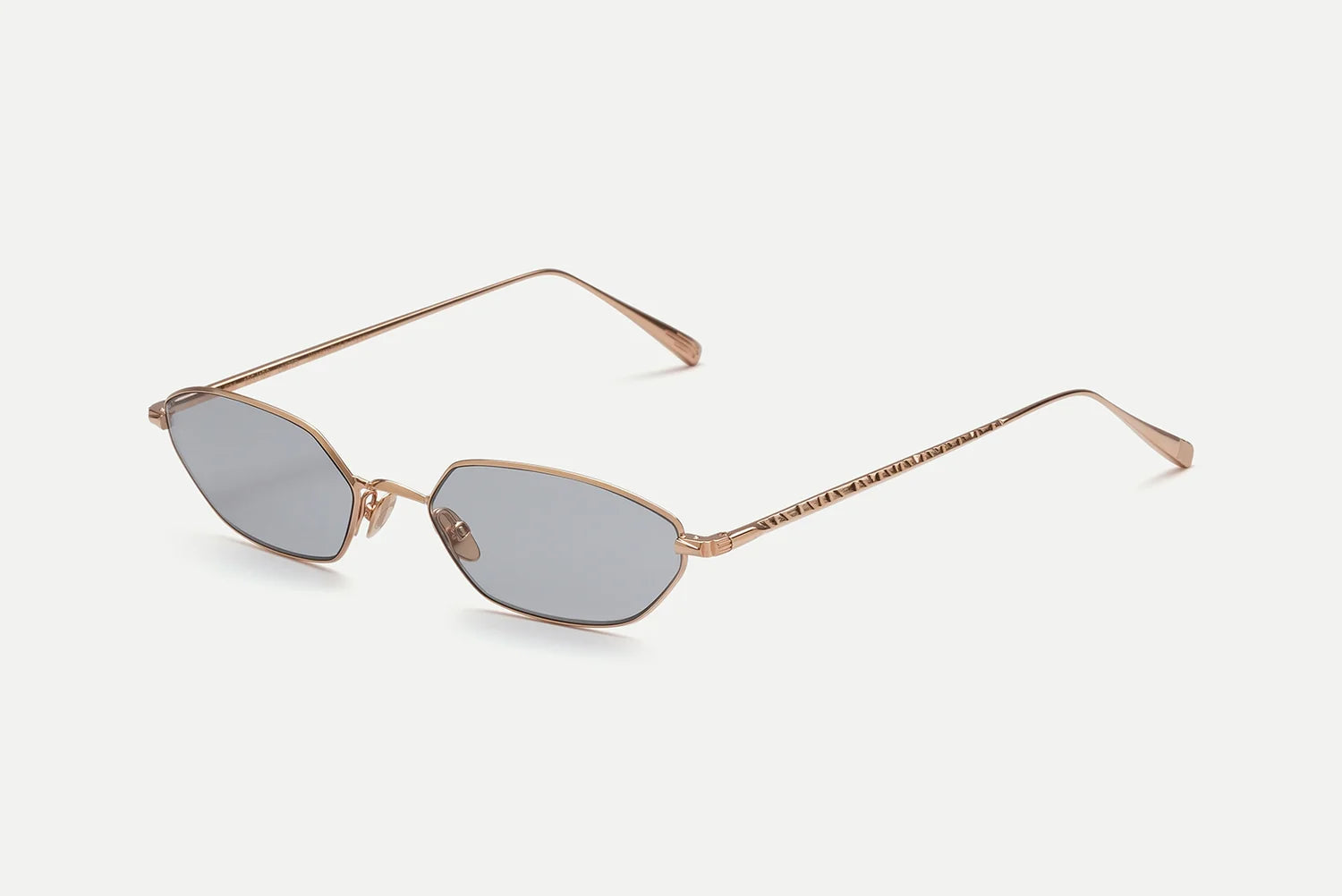 The AHLEM Iris sunglasses by AHLEM feature gold-finished geometric frames with subtly hexagonal gray lenses, displayed here against a white backdrop. Expertly crafted from premium metal eyewear materials, the gold-toned temples and nose pads ensure both sophisticated style and 100% UV protection.