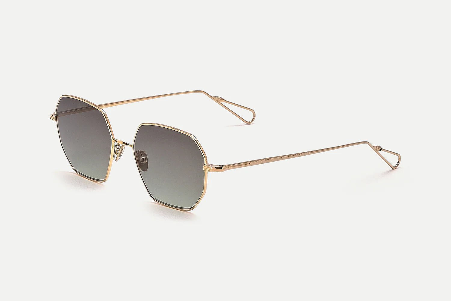 Hexagonal sunglasses with a gold metal frame and gradient gray lenses, shown on a light gray background.