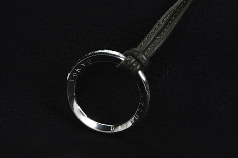 Silver keychain with branding on a black background