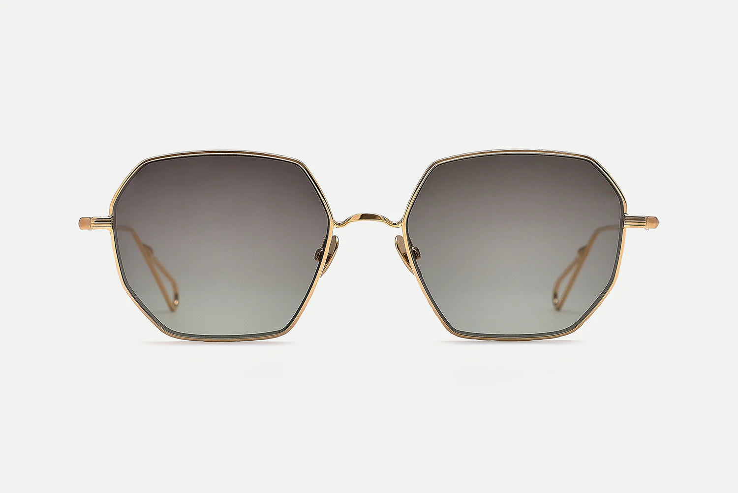 Hexagonal sunglasses with a gold metal frame and gradient gray lenses, shown against a light gray background.