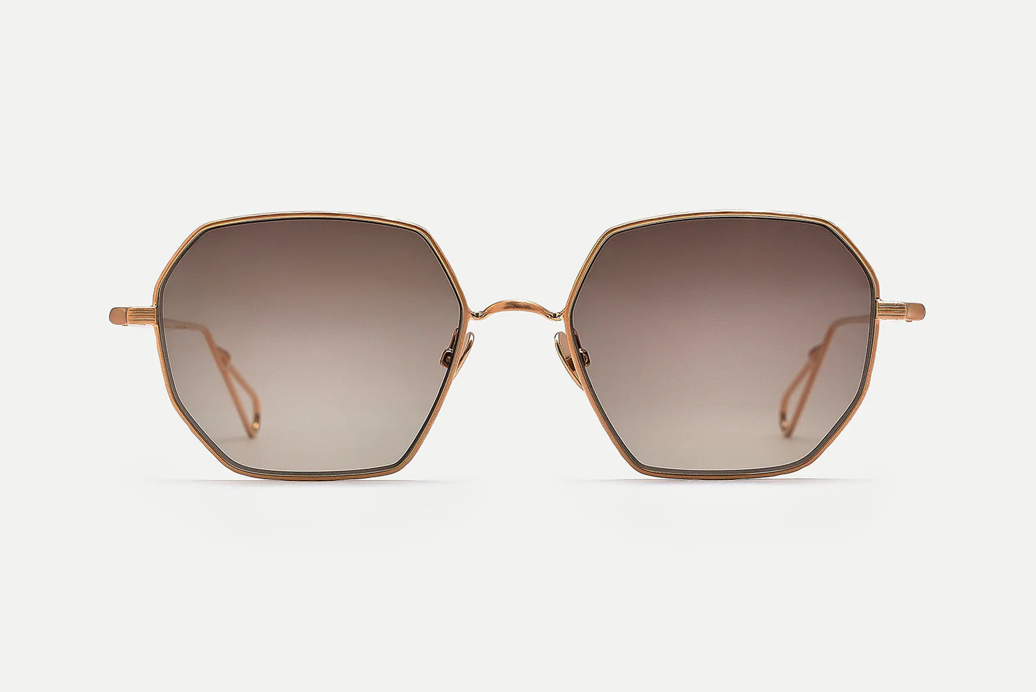 Hexagonal sunglasses with a thin rose gold metal frame and gradient brown lenses, shown against a light gray background.