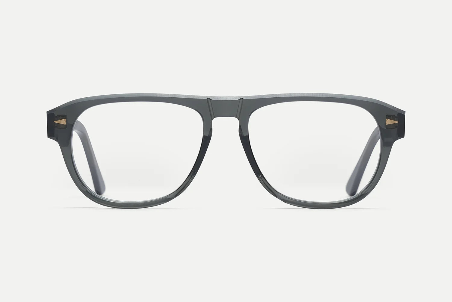 A pair of thick, dark gray acetate eyeglass frames with clear lenses and small gold geometric accents on the temples, shown against a light gray background.