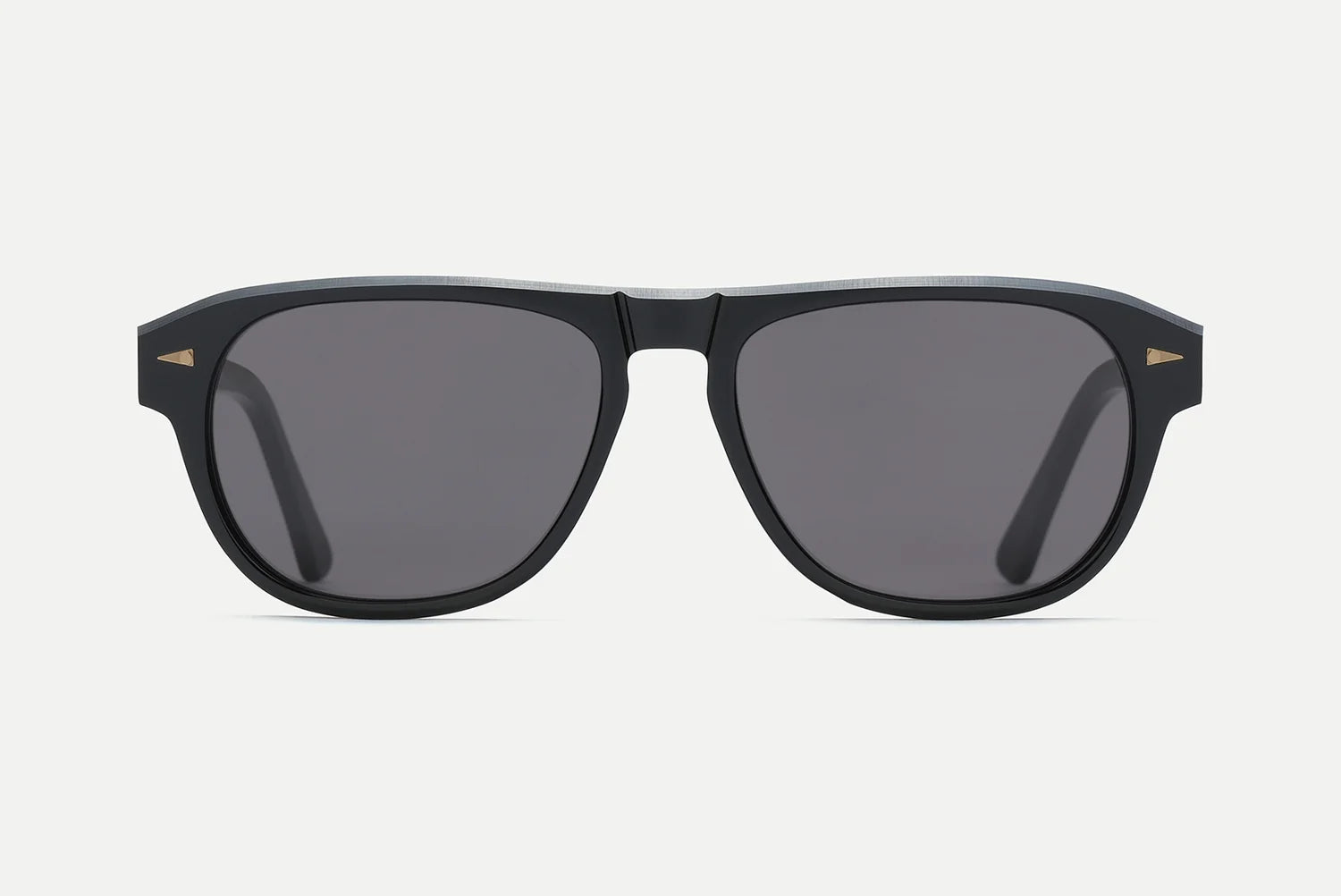 The AHLEM Carpentier sunglasses by AHLEM feature a black pilot-shaped frame handcrafted in France from premium Italian acetate, with dark lenses and a subtle gold triangle detail on each upper corner, presented against a plain white background.