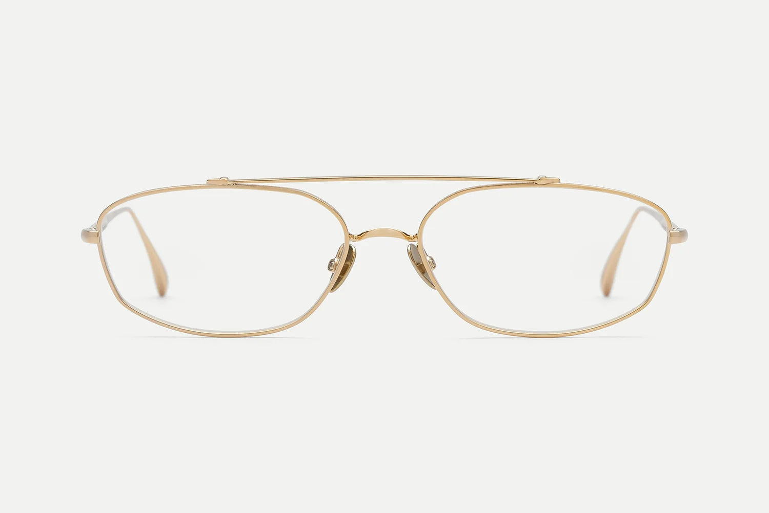 A pair of slim, double-bridge aviator-style eyeglasses in a champagne gold metal frame with clear lenses, shown against a plain light gray background.