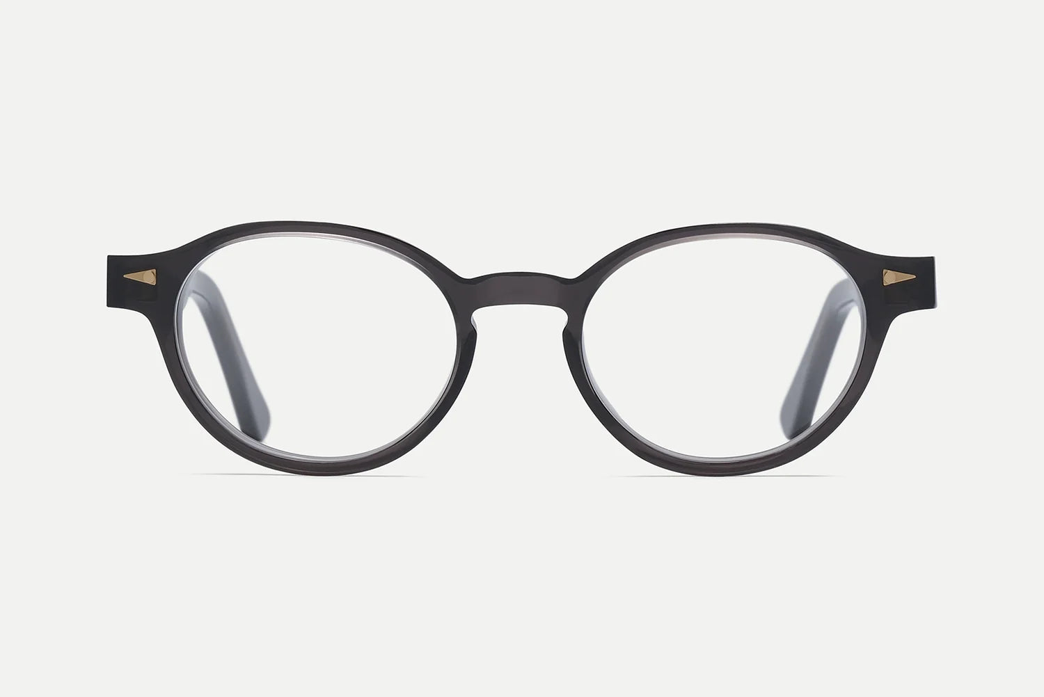 The AHLEM St Marcel by AHLEM are round, black eyeglasses with clear lenses, handcrafted in France from premium Italian acetate. They feature small 22k gold triangle accents near the hinges on both sides and are displayed against a plain white background.
