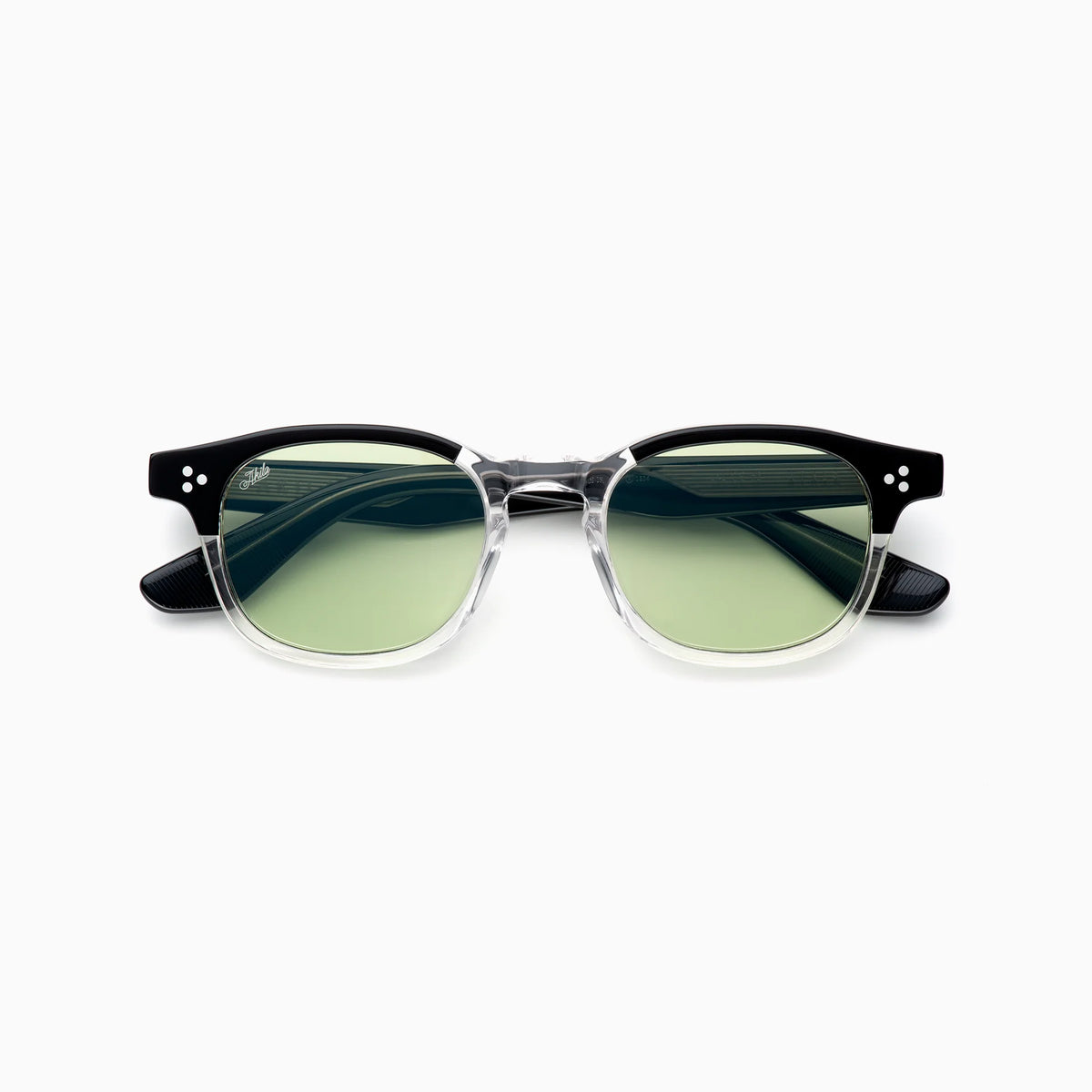 Akila Atria eyeglasses by Akila, featuring clear frames with black upper rims and green-tinted lenses, showcase a balanced silhouette and medium fit, displayed on a white background.