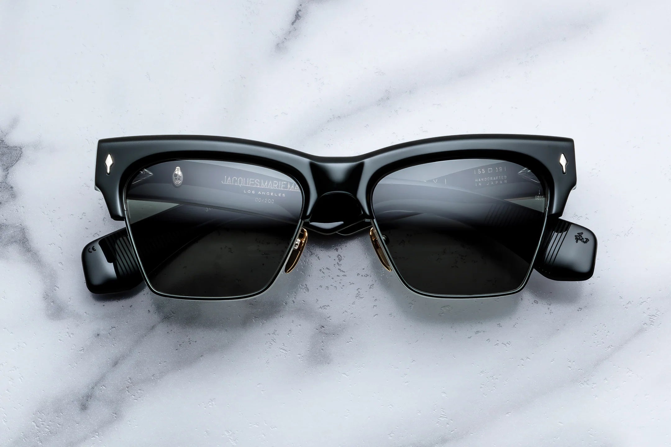Black sunglasses with gold accents on a marble surface