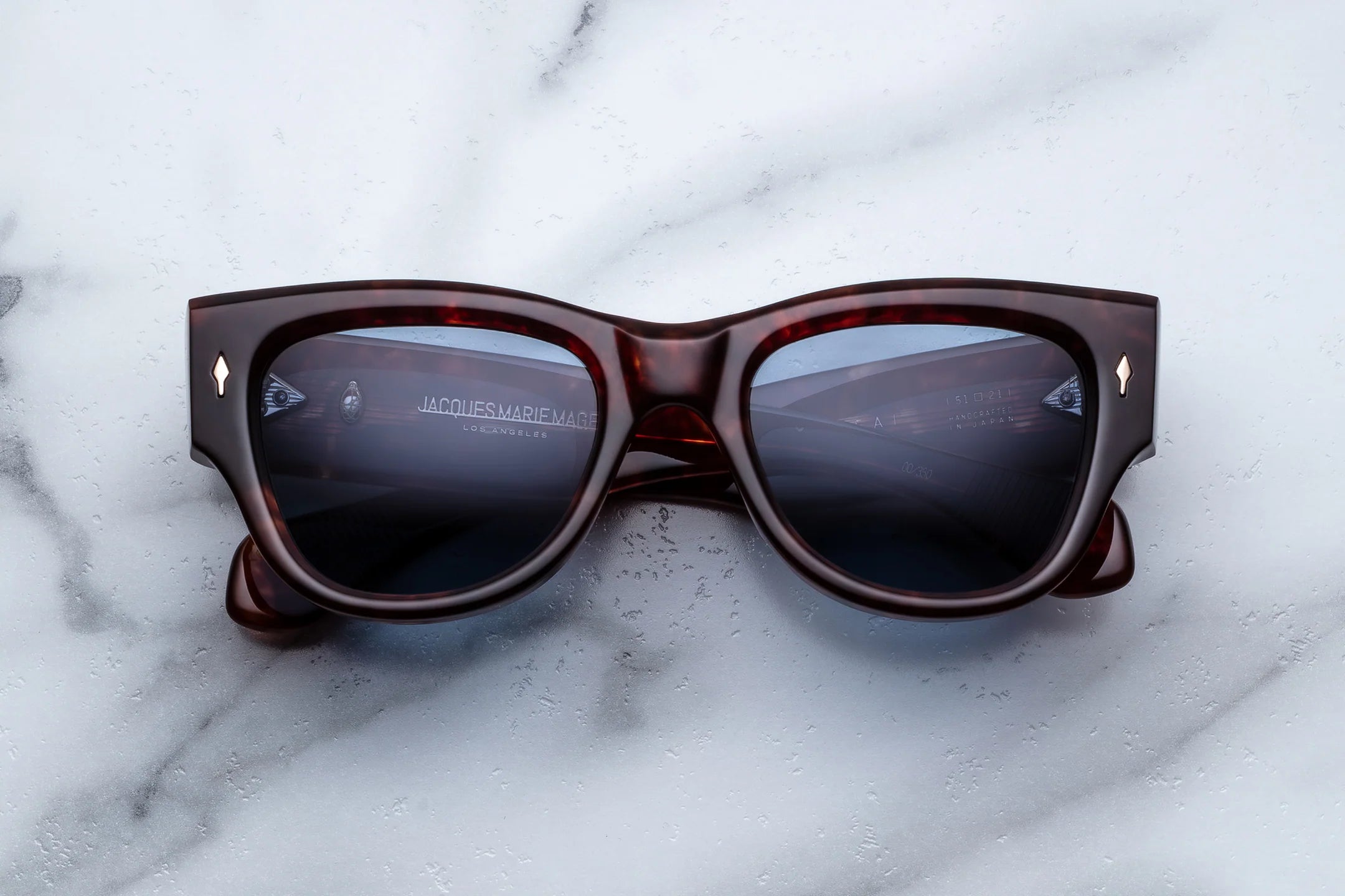 Sunglasses with tortoiseshell frame and dark lenses on a marble surface
