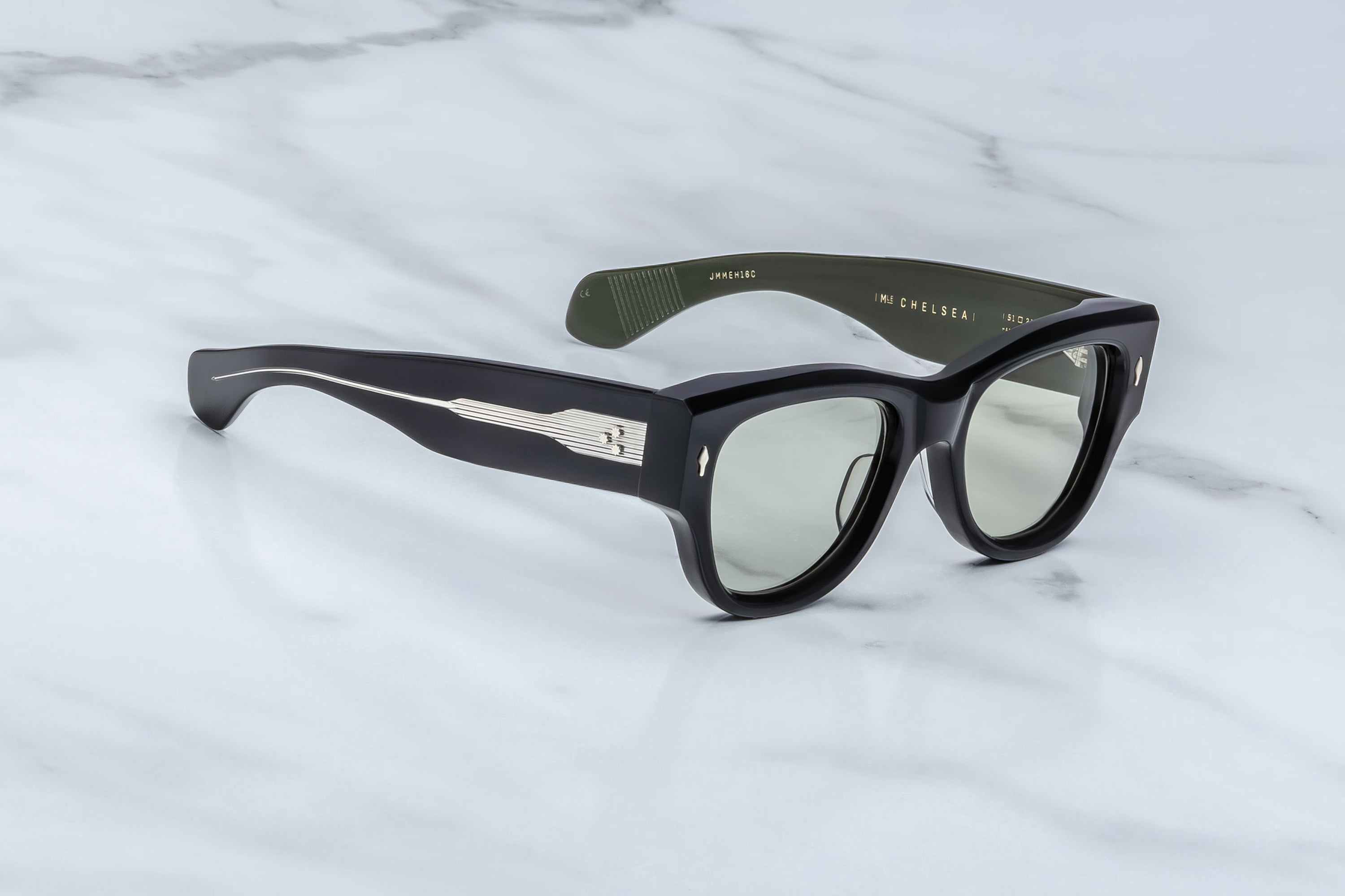 Black sunglasses with a brand logo on a light gray marble background