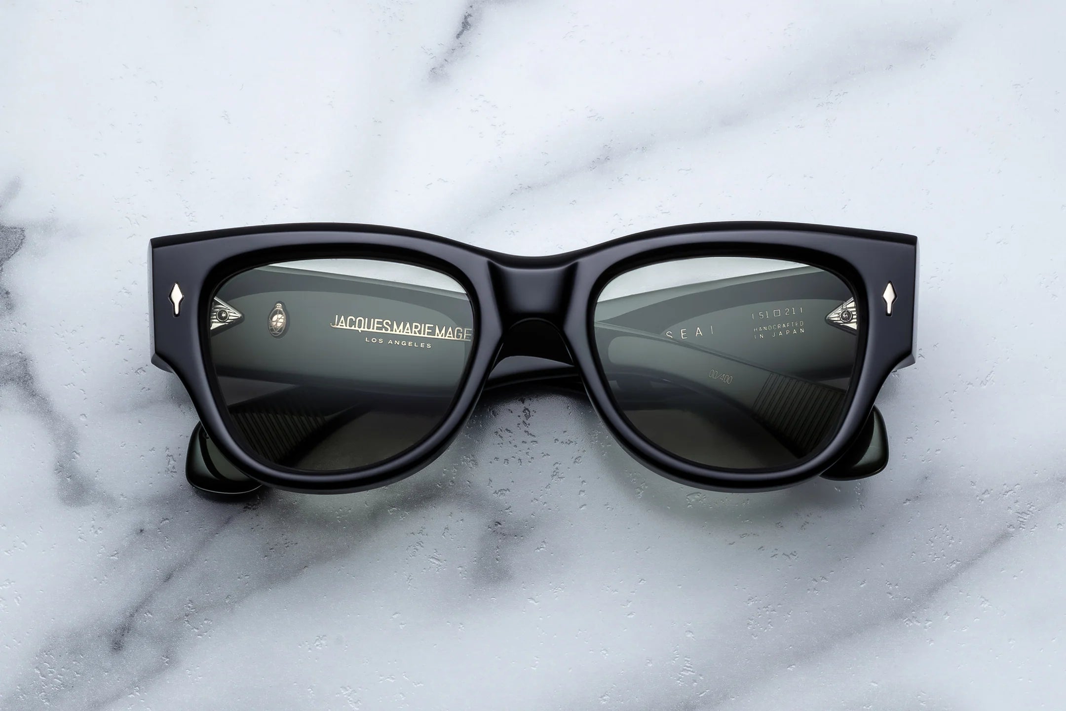 Black sunglasses with gold accents on a marble surface