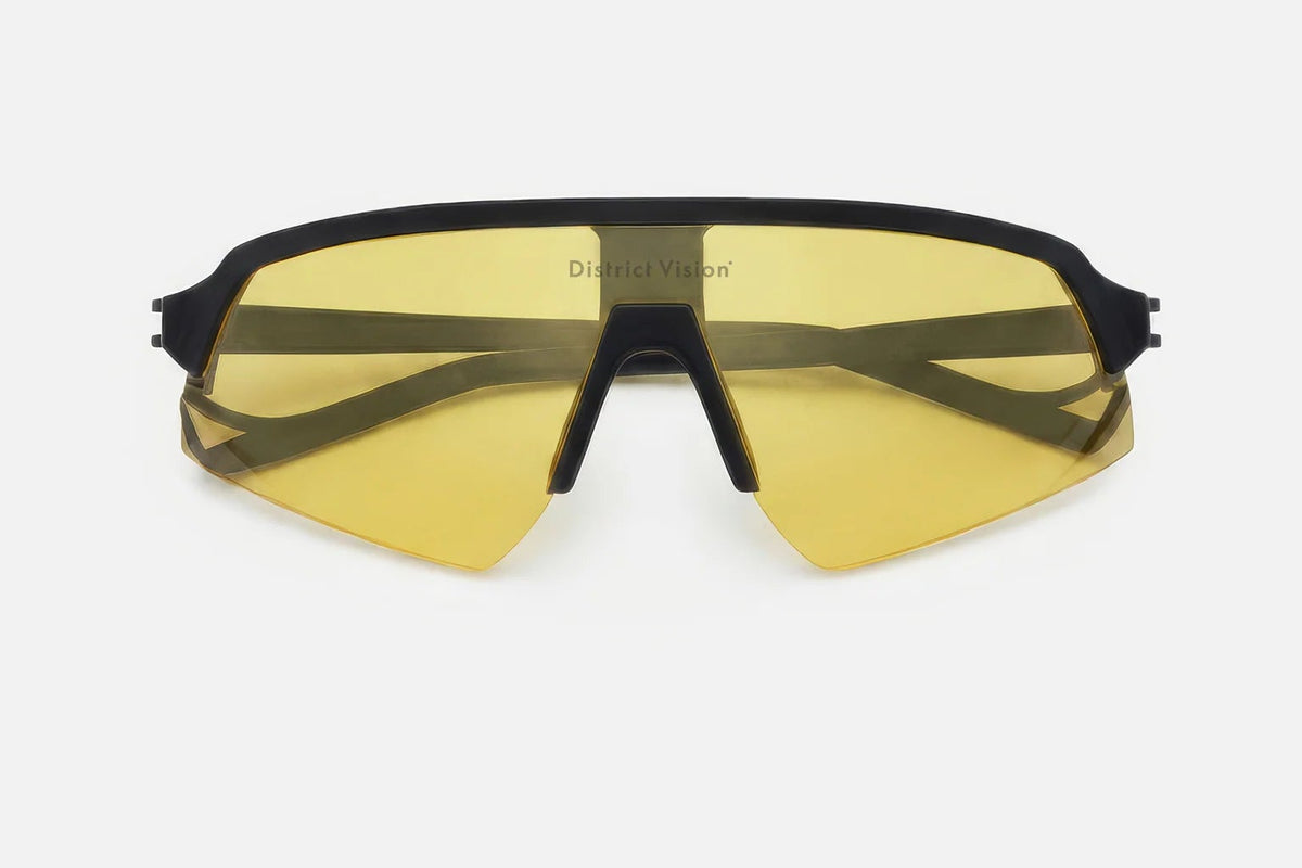 District Vision Choji Turbo Blade sports sunglasses featuring therapeutic grade, yellow-tinted lenses and a black frame, displayed front-facing on a white background. The District Vision logo is printed at the top center of the lens for superior eye protection.
