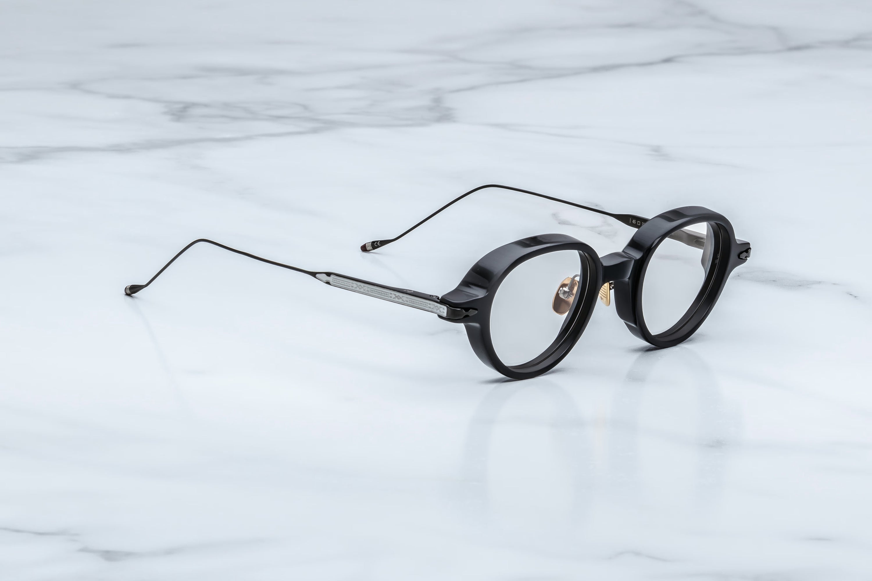 Round eyeglasses with black frames on a light marble background
