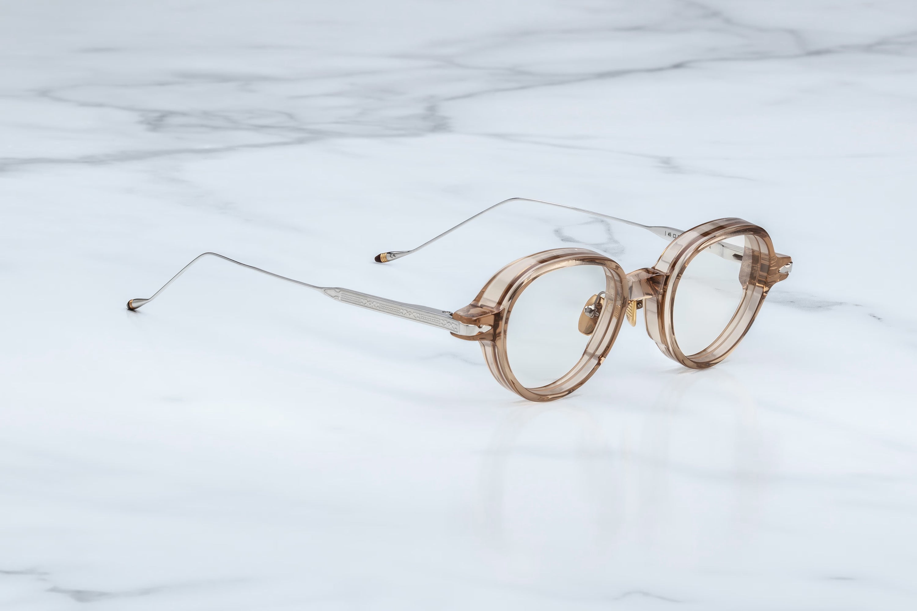 Round eyeglasses with gold frame on a marble background