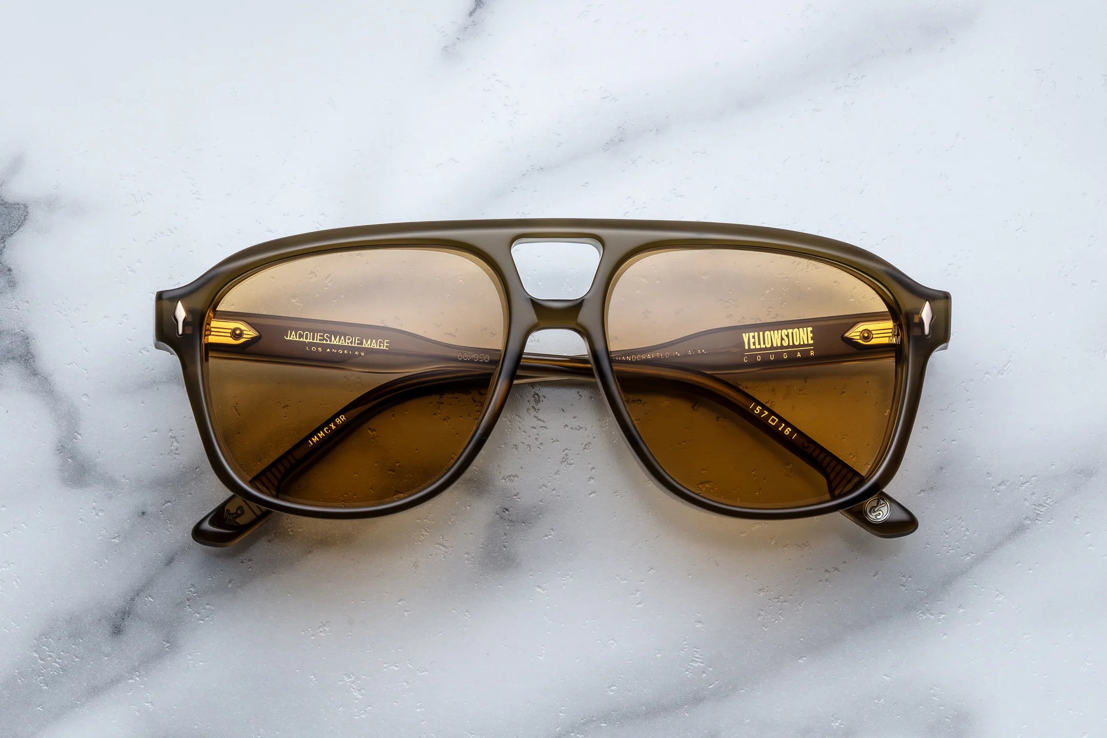 JMM Sunglasses with brown lenses on a marble surface