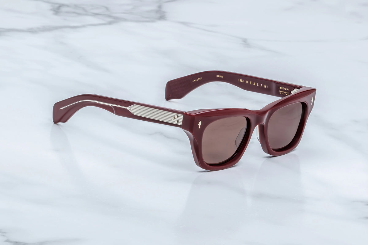 Burgundy rectangular Jacques Marie Mage Dealan sunglasses with silver metal temple details, channeling an artist-inspired aesthetic reminiscent of ‘60s eyewear.
