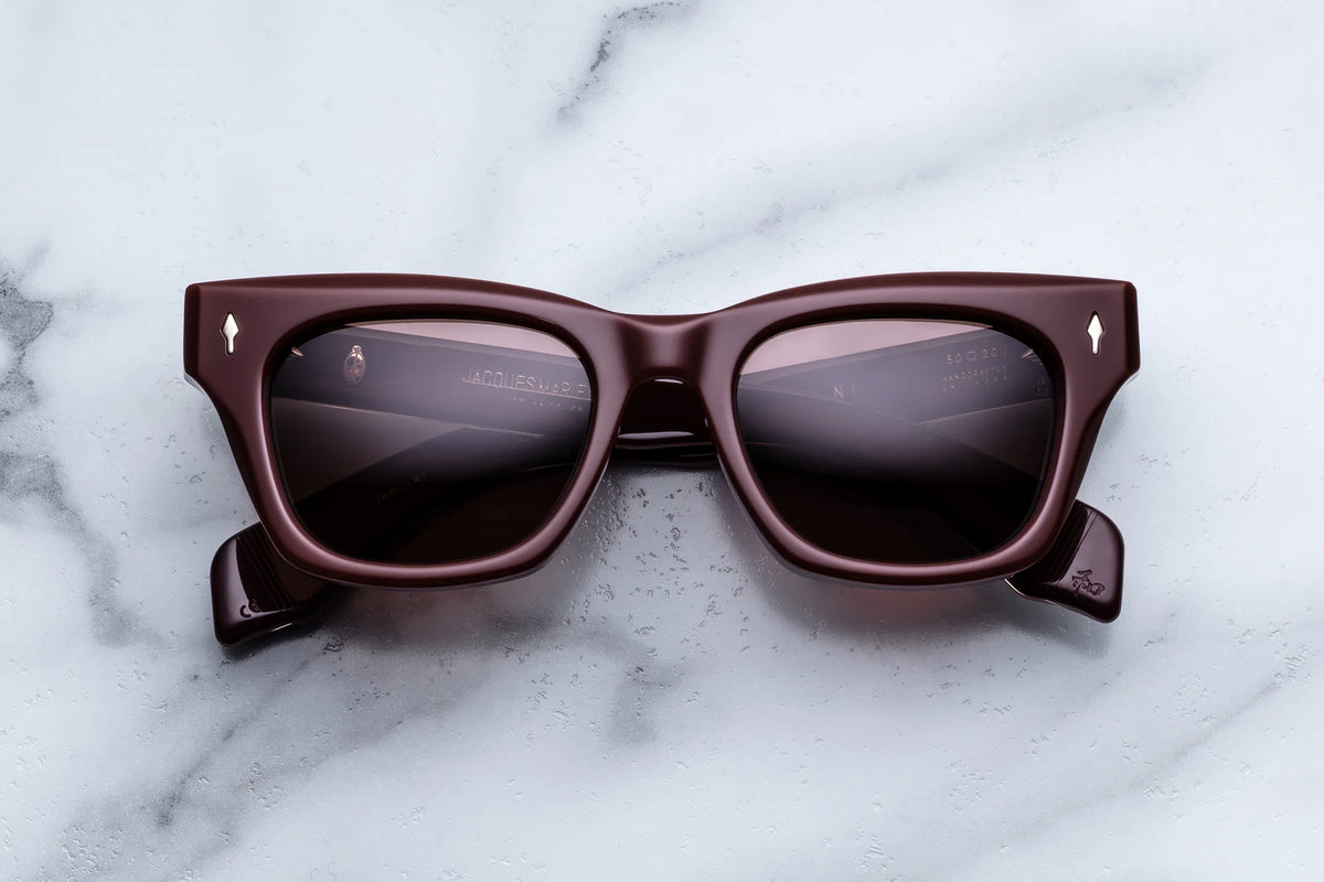 Dark burgundy rectangular Jacques Marie Mage Dealan sunglasses featuring silver arrow accents on the front frame corners.
