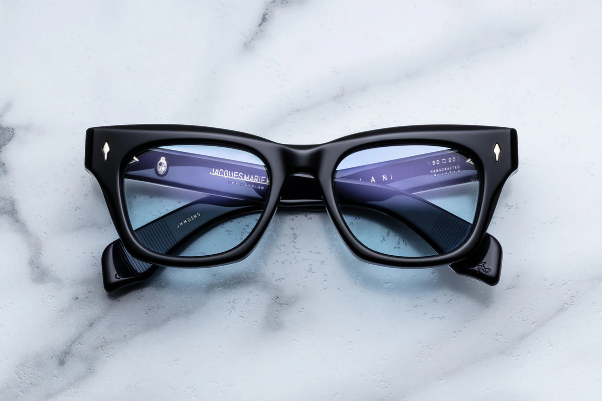 Black-framed Jacques Marie Mage Dealan rectangular eyeglasses with light blue tinted lenses in an artist-inspired style.