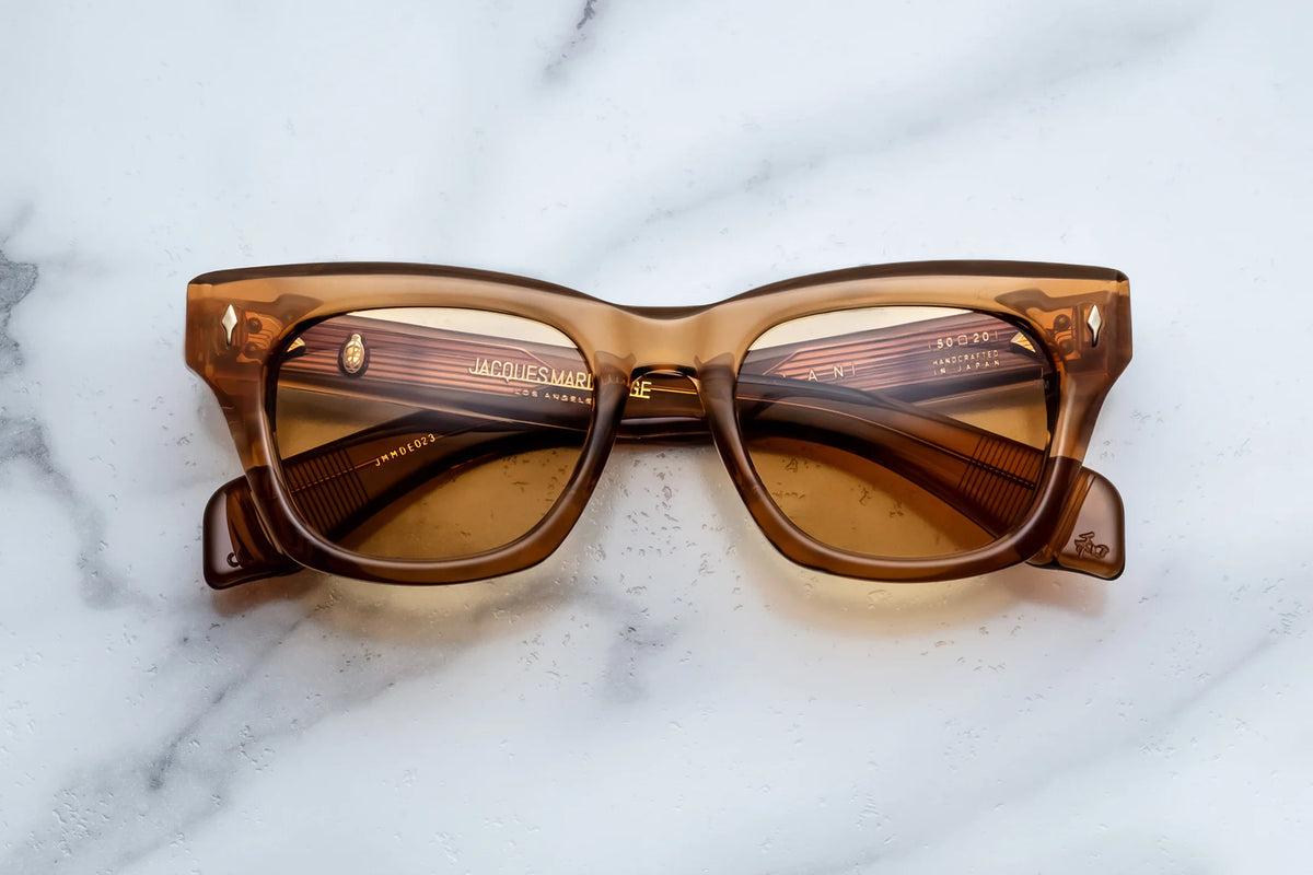 Jacques Marie Mage Dealan translucent brown cat-eye sunglasses with custom photochromic lenses resting on a white marble surface.