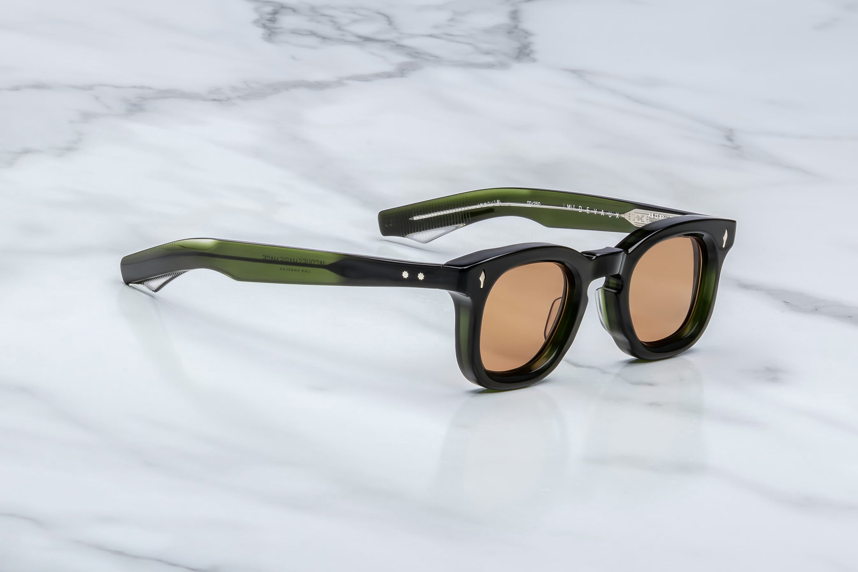 Sunglasses with green frames and brown lenses on a marble surface