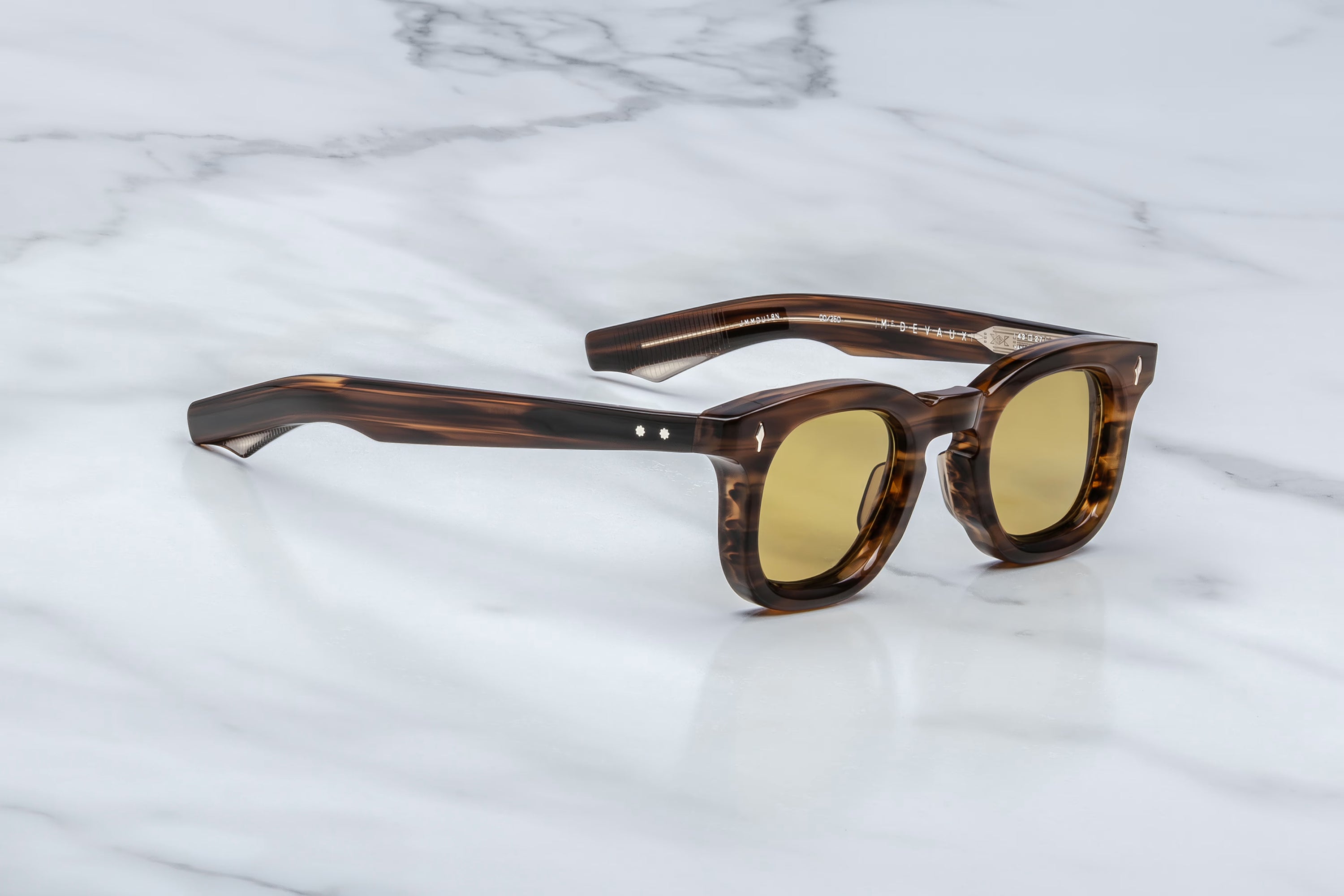 Brown tortoiseshell sunglasses with gold lenses on a marble surface