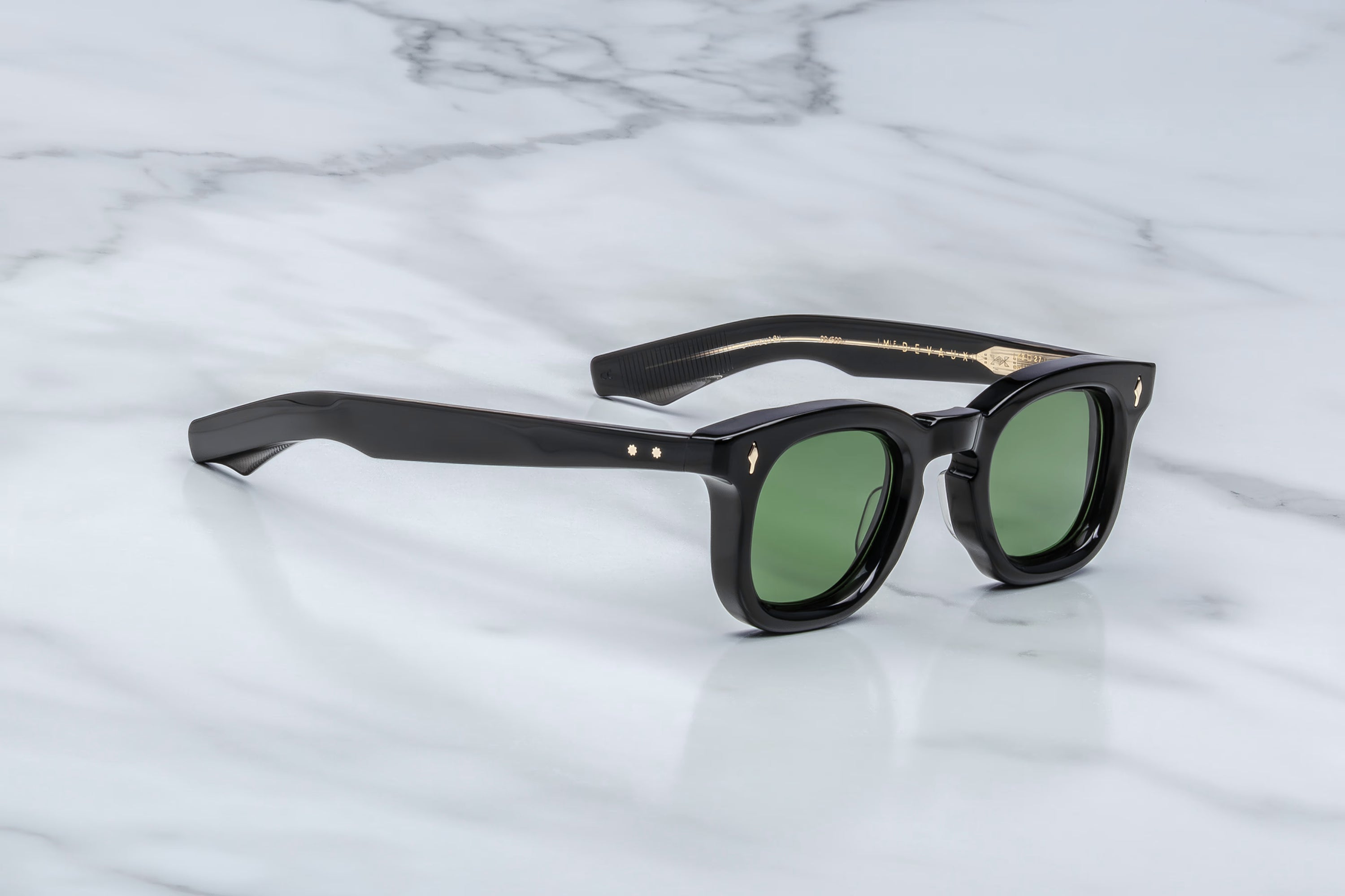 Black sunglasses with green lenses on a marble surface