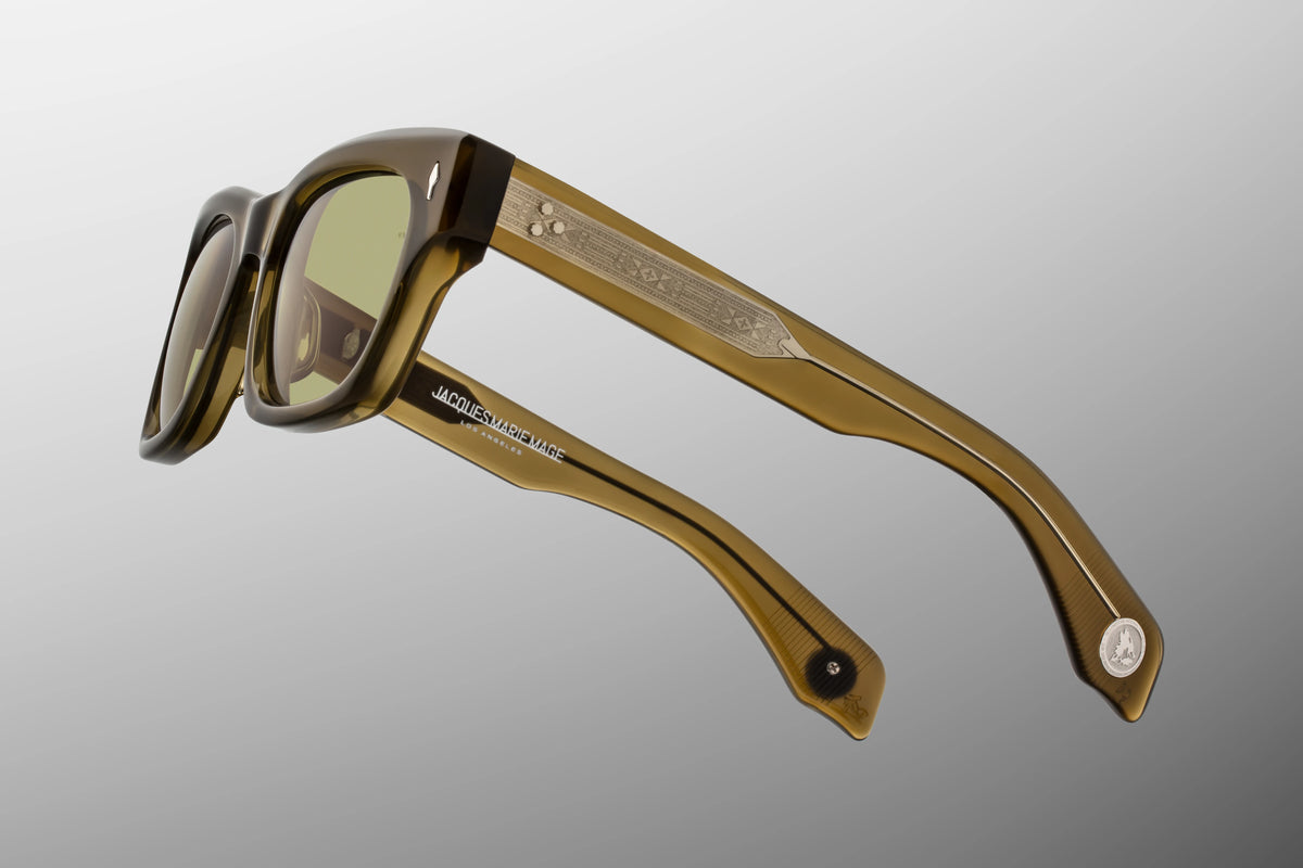 Jacques Marie Mage Yellowstone VII: Haynes In Green Moss spectacles, featuring ’60s-inspired olive green rectangular frames, tinted lenses, and intricate metal detailing on the handcrafted acetate temples.