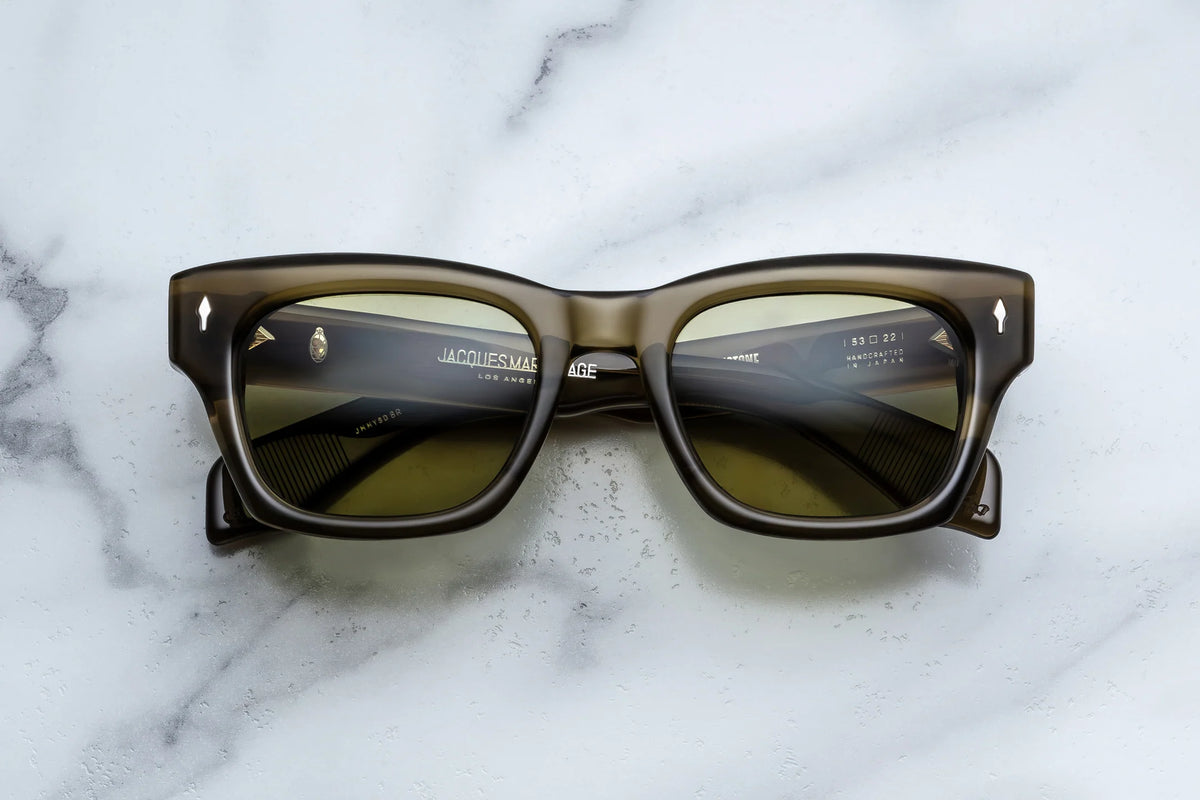 Jacques Marie Mage Yellowstone VII: Haynes In Green Moss sunglasses, featuring olive-green rectangular frames with ’60s-inspired gold-tone accents at the corners.