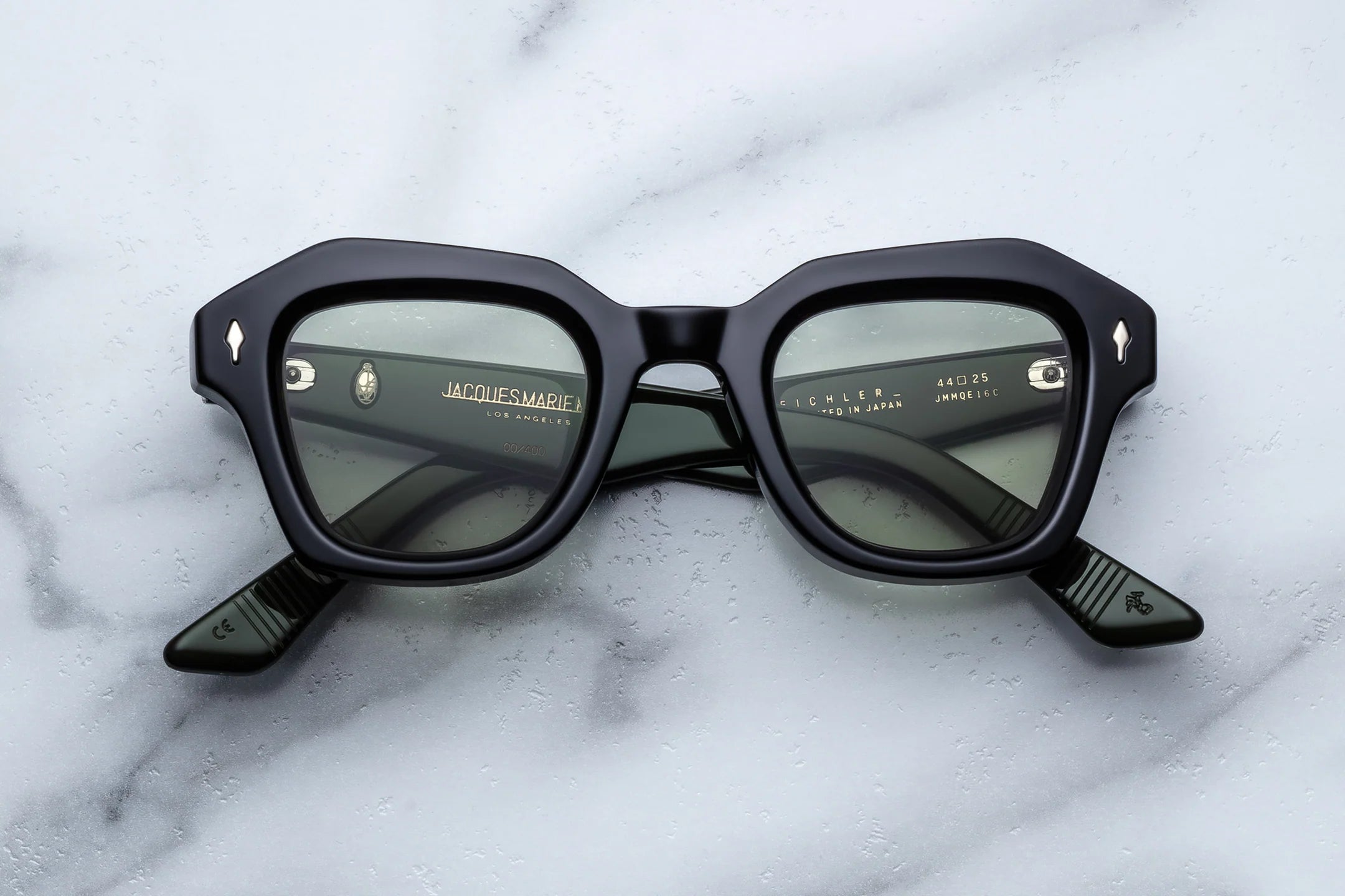 Black sunglasses with 'Jacobs & Co.' branding on a white marble surface