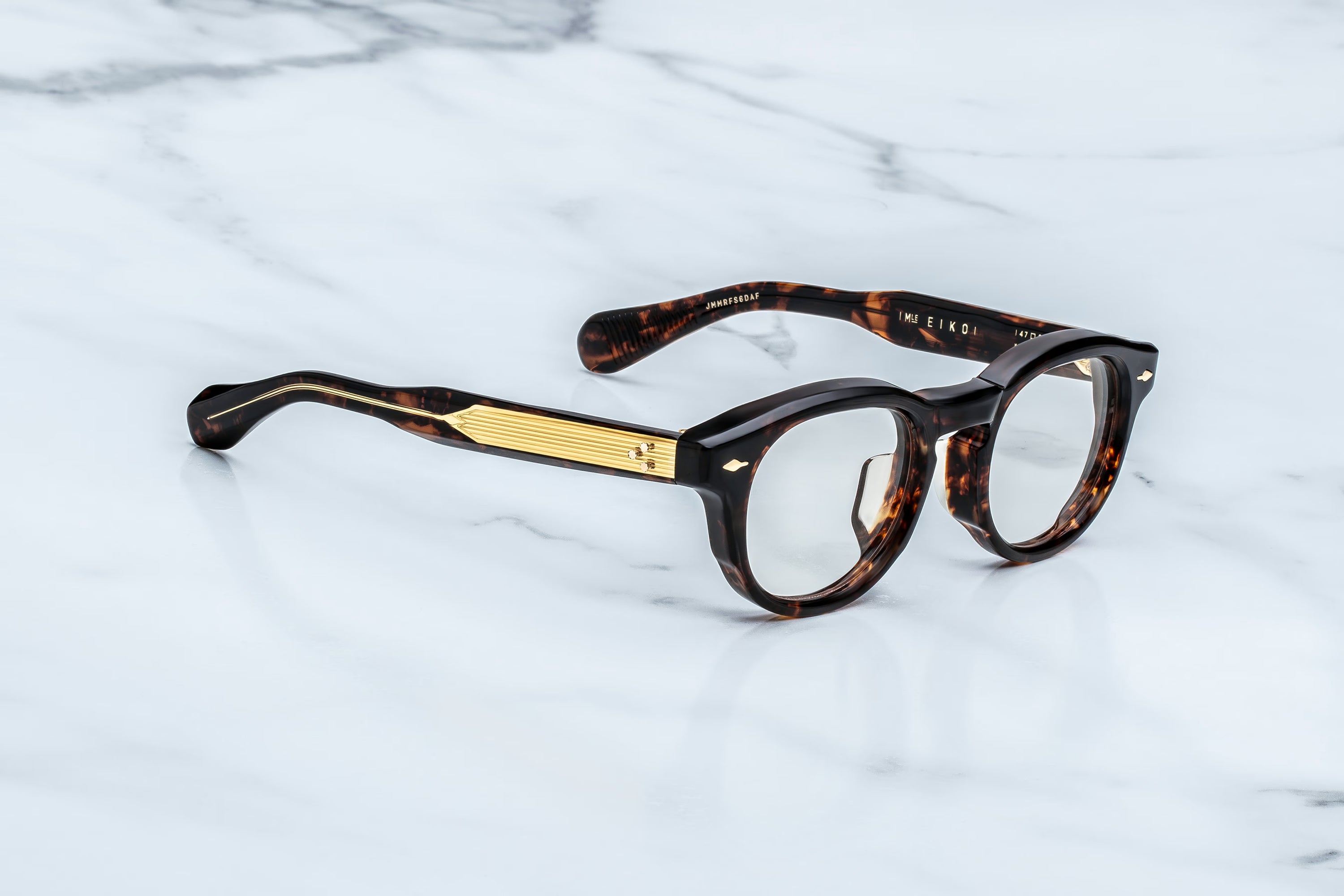 Tortoiseshell eyeglasses with gold accents on a marble surface