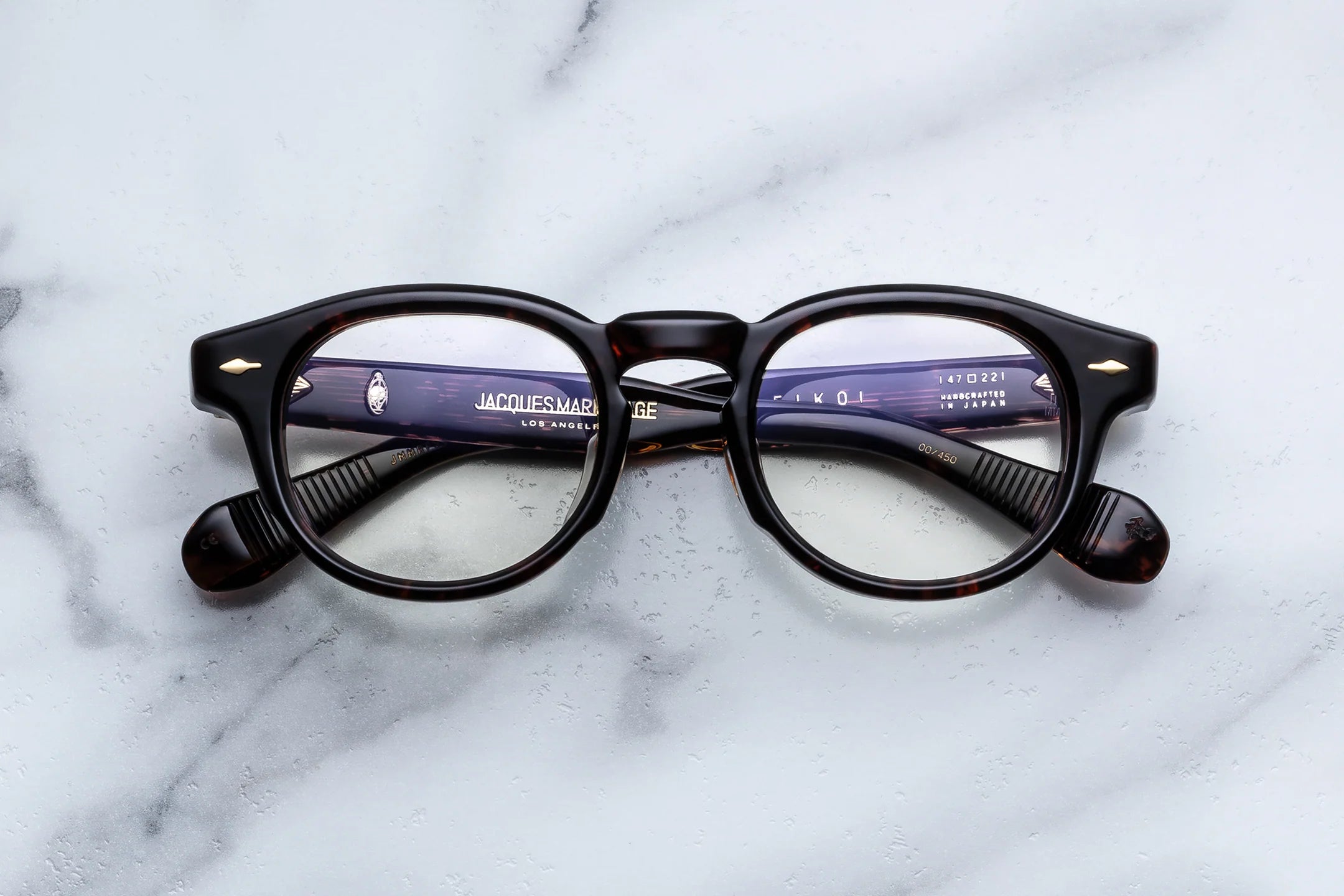 Black eyeglasses with a visible brand logo on a marble surface
