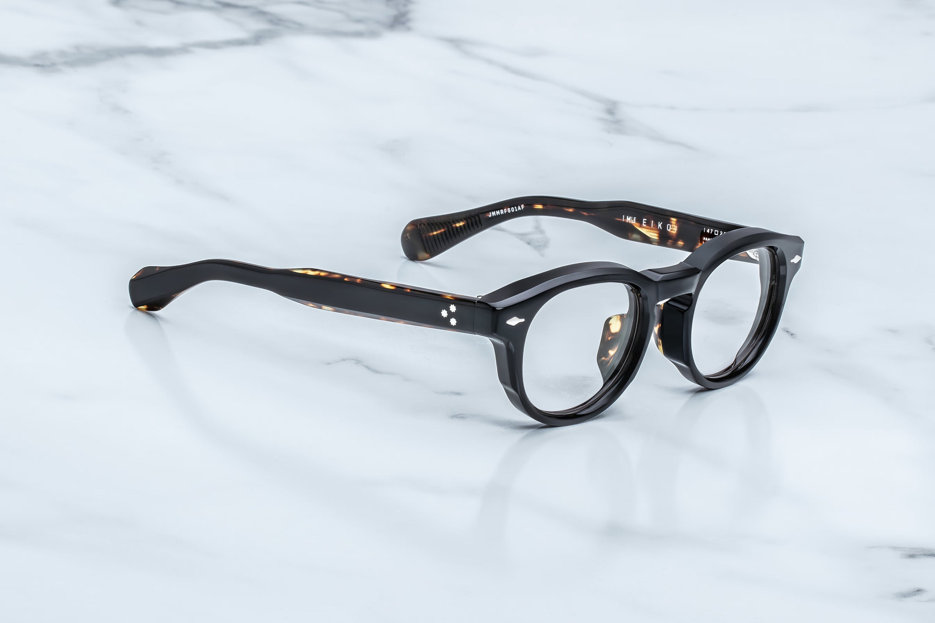 Round eyeglasses with tortoiseshell frame on a marble surface
