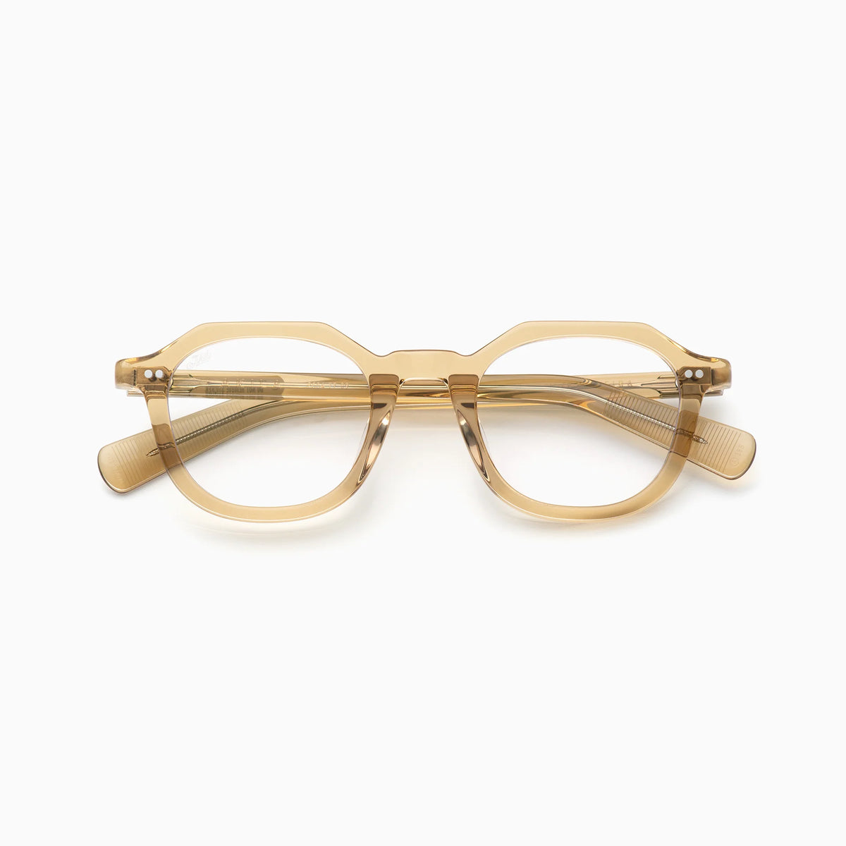 The Akila Eira optical frames by Akila feature a tan color and a geometric, octagonal design, shown from the front against a white background. These glasses have clear lenses with subtle metallic rivets on the temples near the hinges, combining classic style with modern blue light blocking technology.
