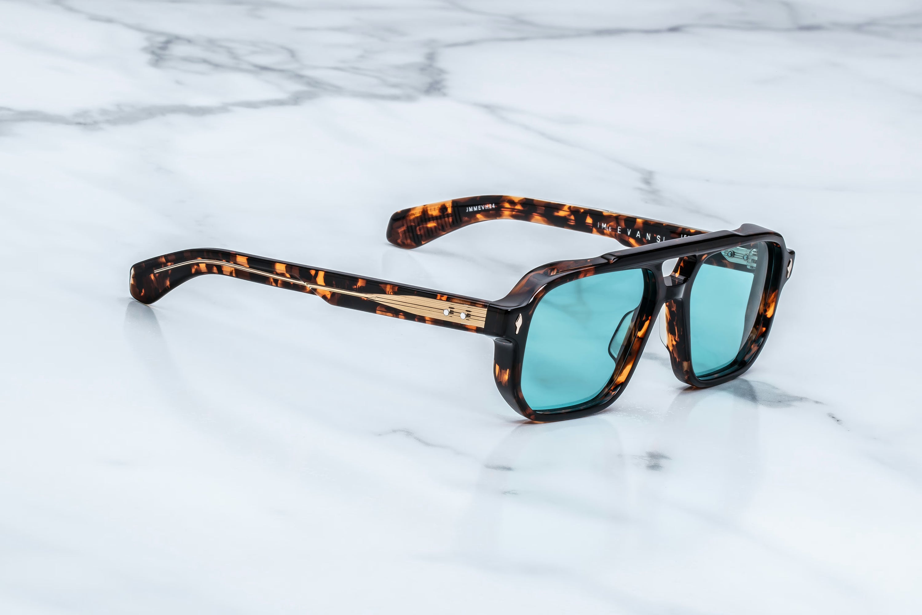 A pair of square-frame sunglasses with a dark brown and black tortoiseshell pattern and light blue lenses, resting on a white marble surface.