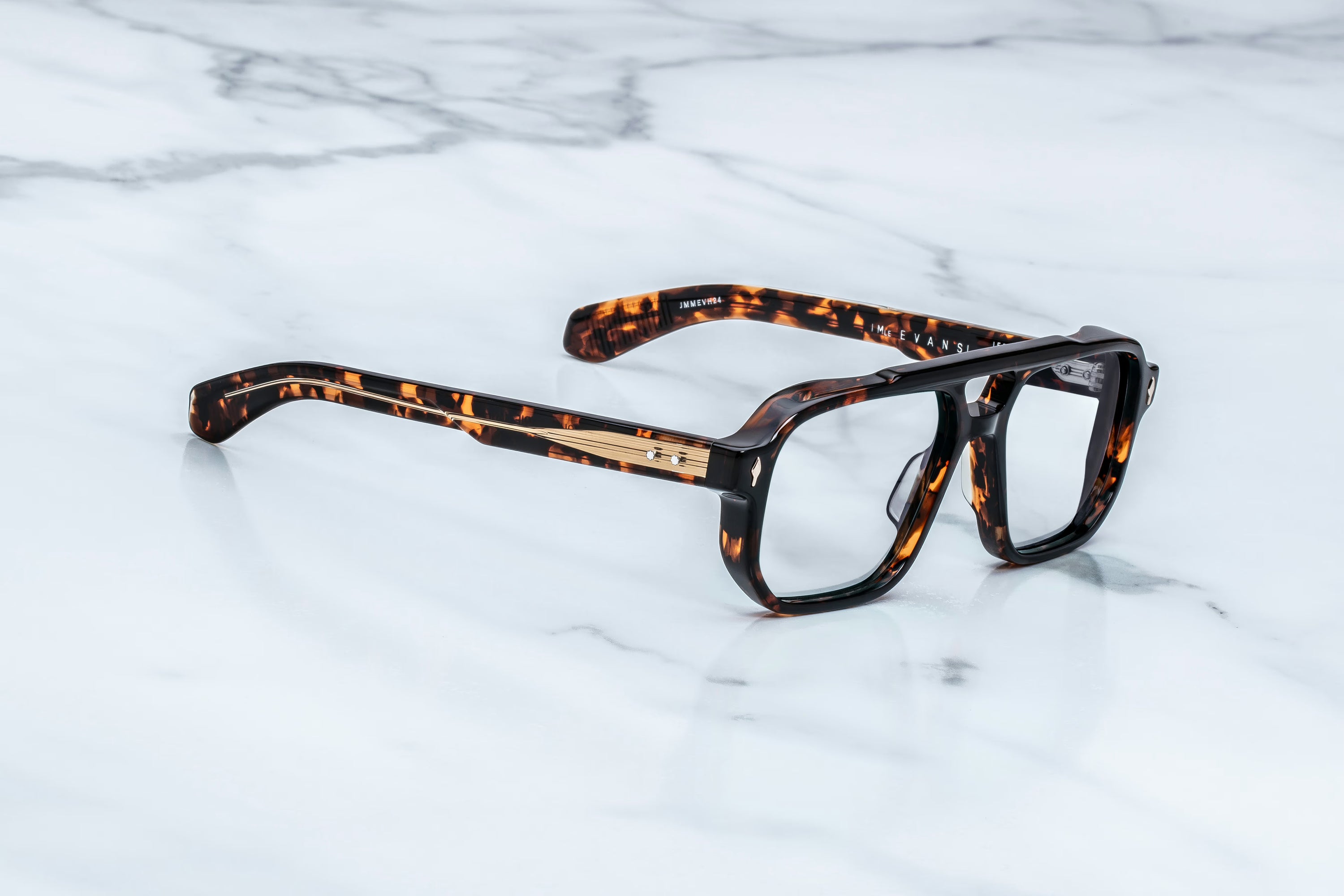 A pair of square-frame eyeglasses with a glossy black and brown tortoiseshell pattern, resting on a white marble surface.