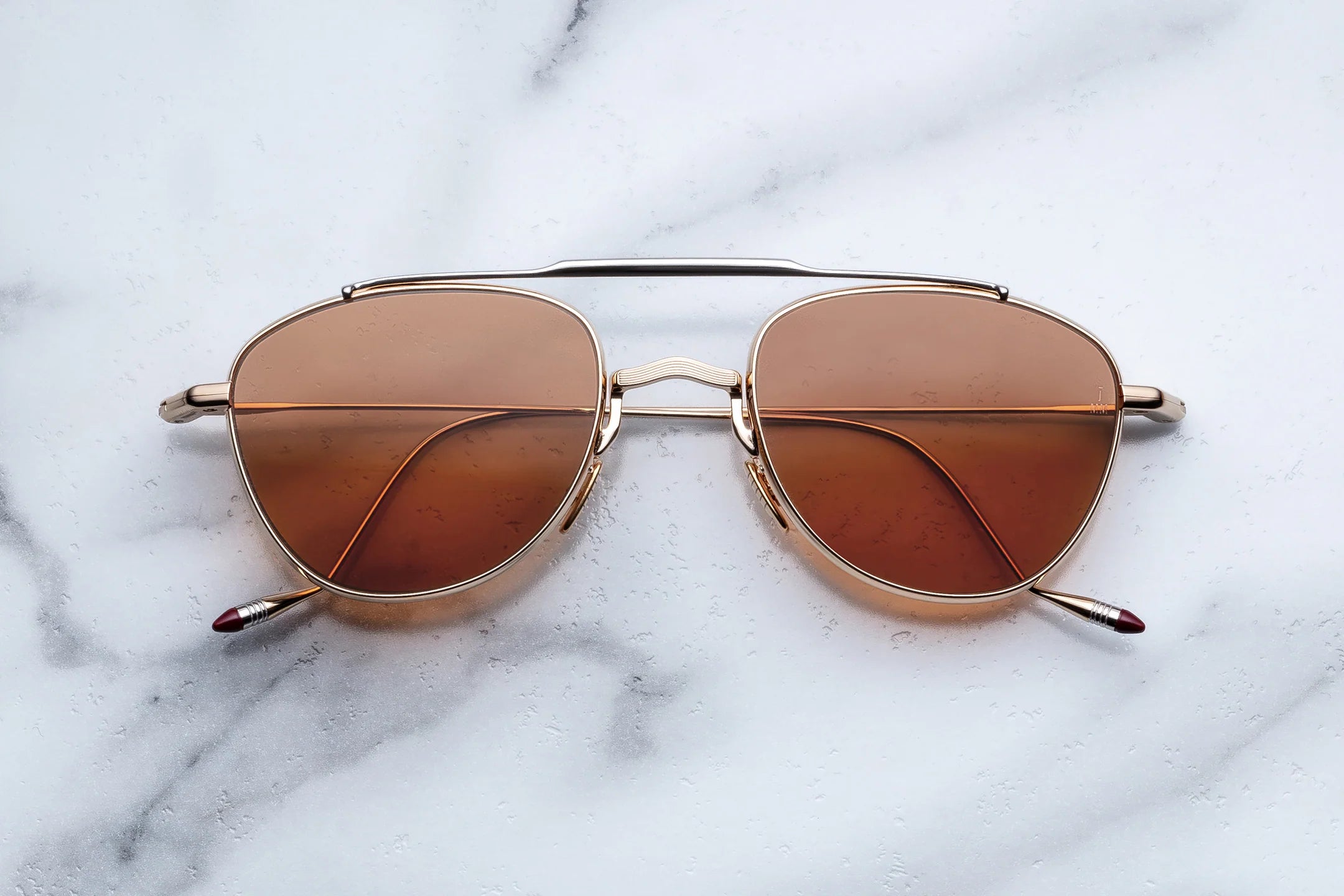 Aviator sunglasses with brown lenses on a marble surface