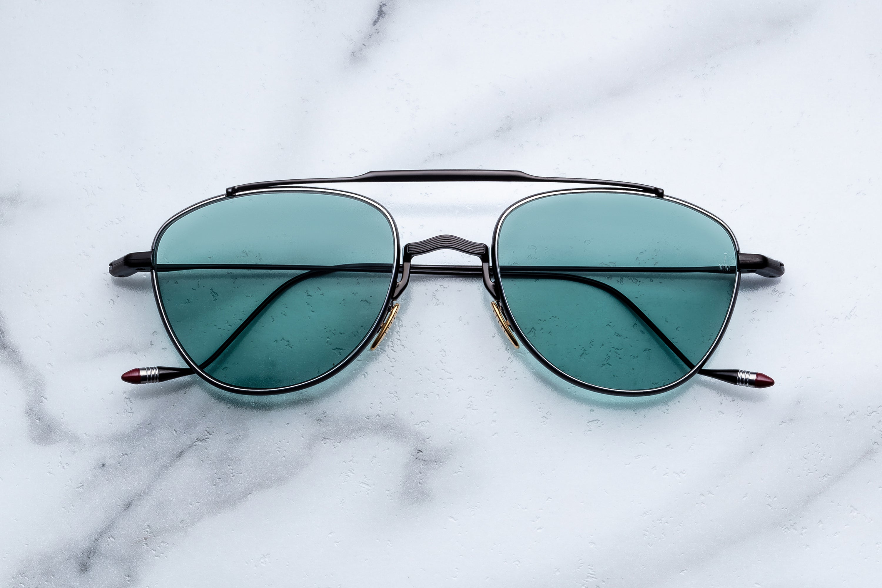Aviator sunglasses with teal lenses on a marble surface