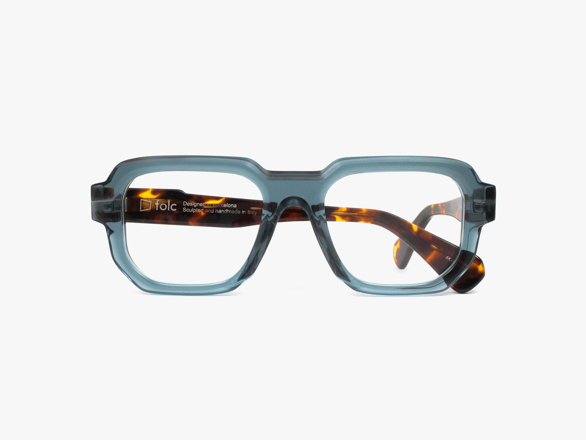 Folc Gurb eyewear featuring translucent blue-grey, thick, angular frames with tortoiseshell inner temples.